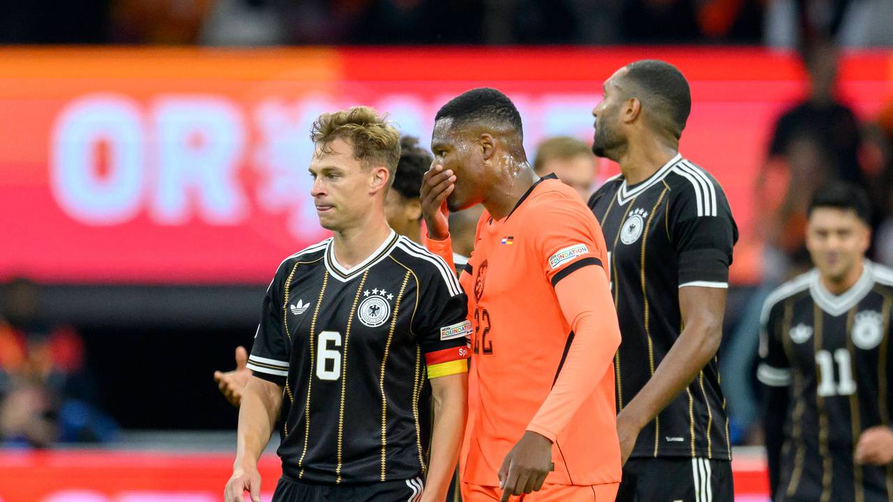 Denzel Dumfries sagt etwas zu Joshua Kimmich und hält dabei die Hand vors Gesicht.