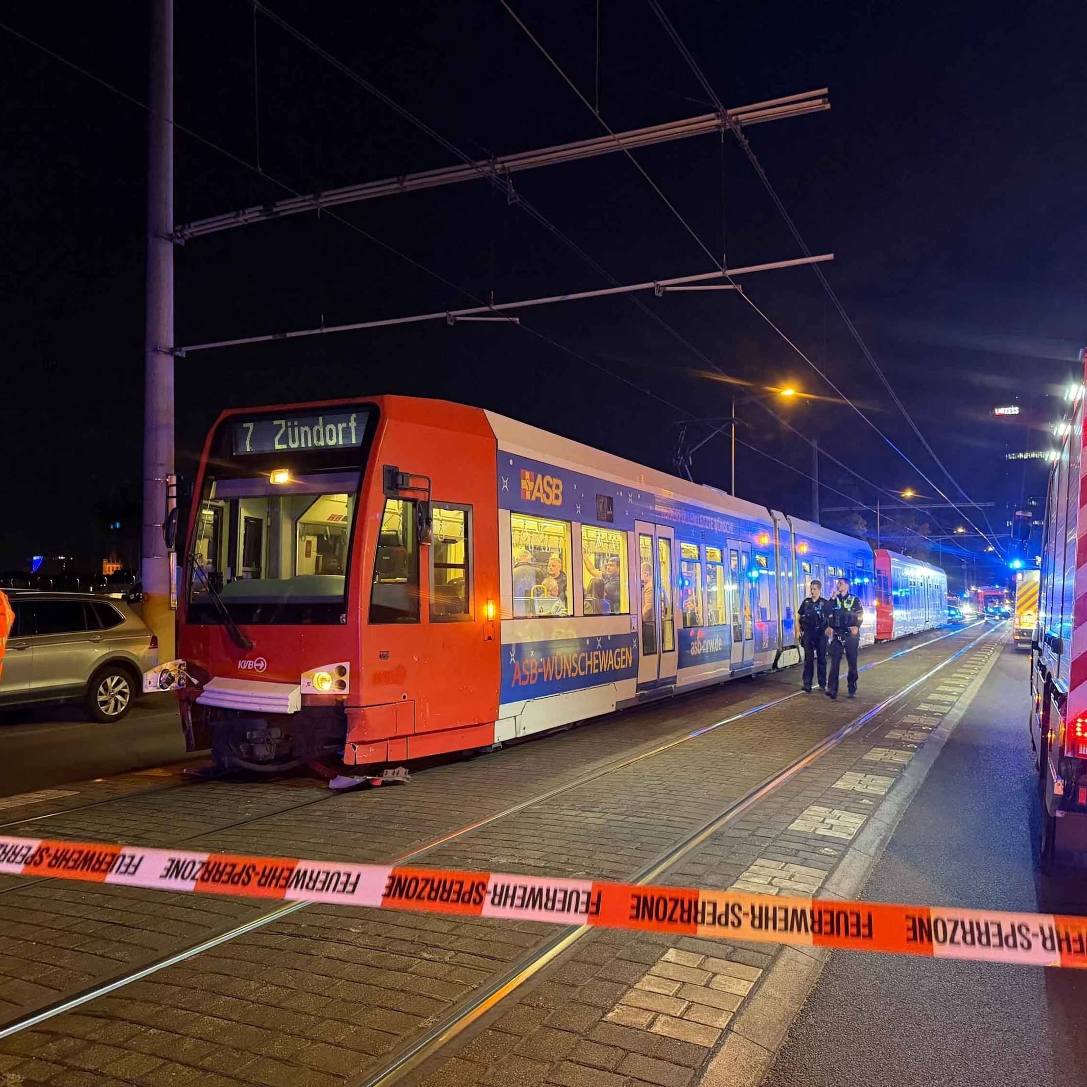 Die Polizei hat eine Unfallstelle in Köln mit Flatterband abgesperrt, davor steht eine Bahn der Linie 7.