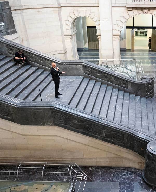 Belit Onay steht auf einer breiten Treppe und spricht zur zahlreichen Presseleuten, die sich am Fuß der Treppe knubbeln.