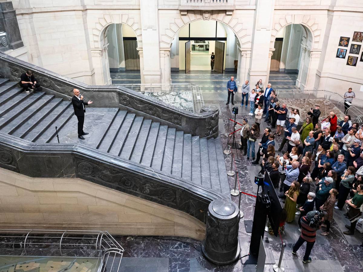 Belit Onay steht auf einer breiten Treppe und spricht zur zahlreichen Presseleuten, die sich am Fuß der Treppe knubbeln.