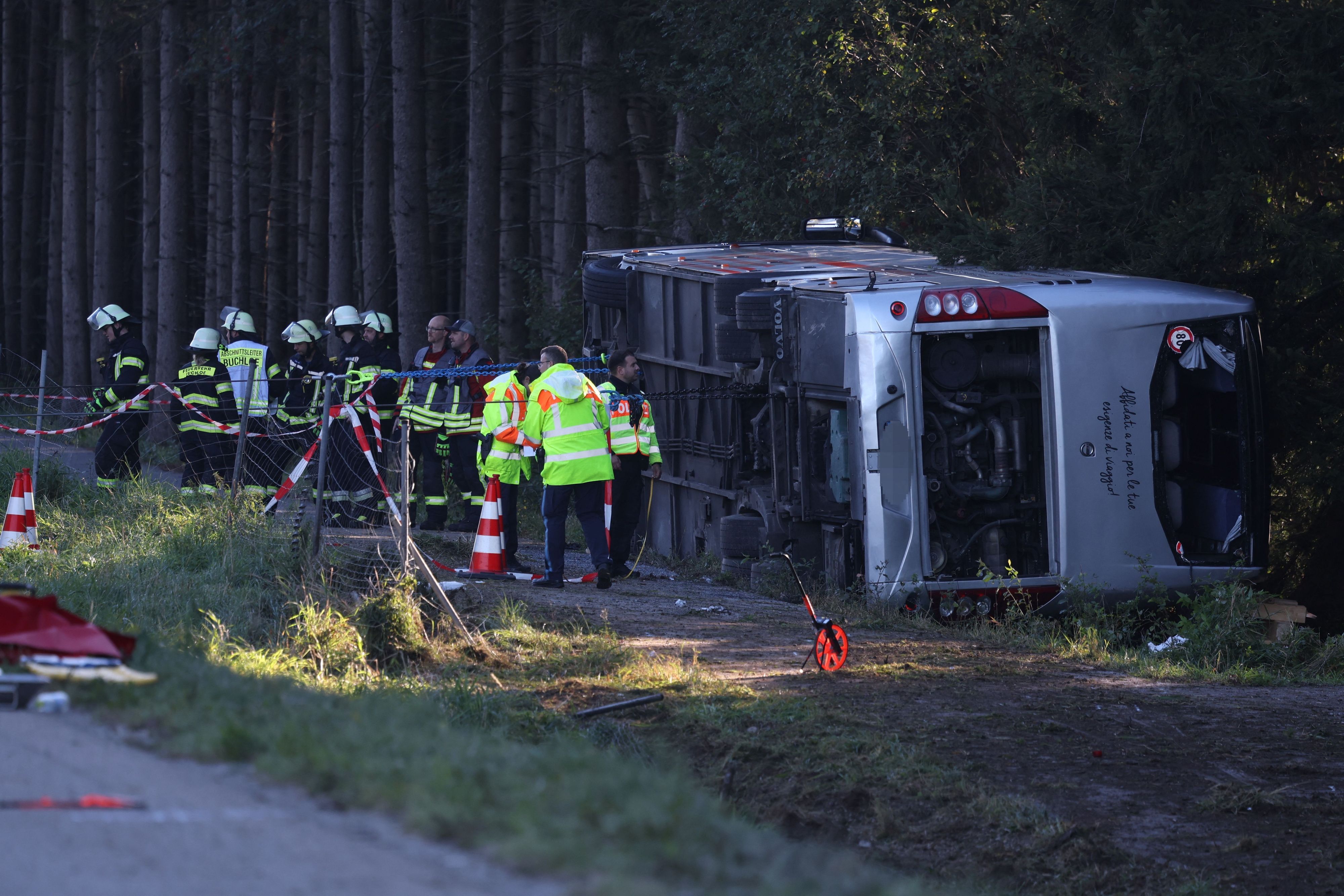Kräfte von Feuerwehr und Polizei sind an einem Bus im Einsatz, der auf der Seite liegt.