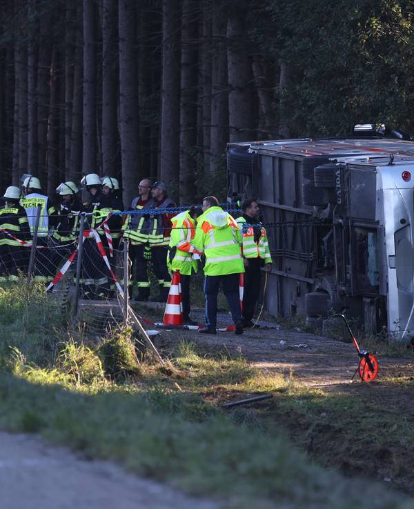 Kräfte von Feuerwehr und Polizei sind an einem Bus im Einsatz, der auf der Seite liegt.