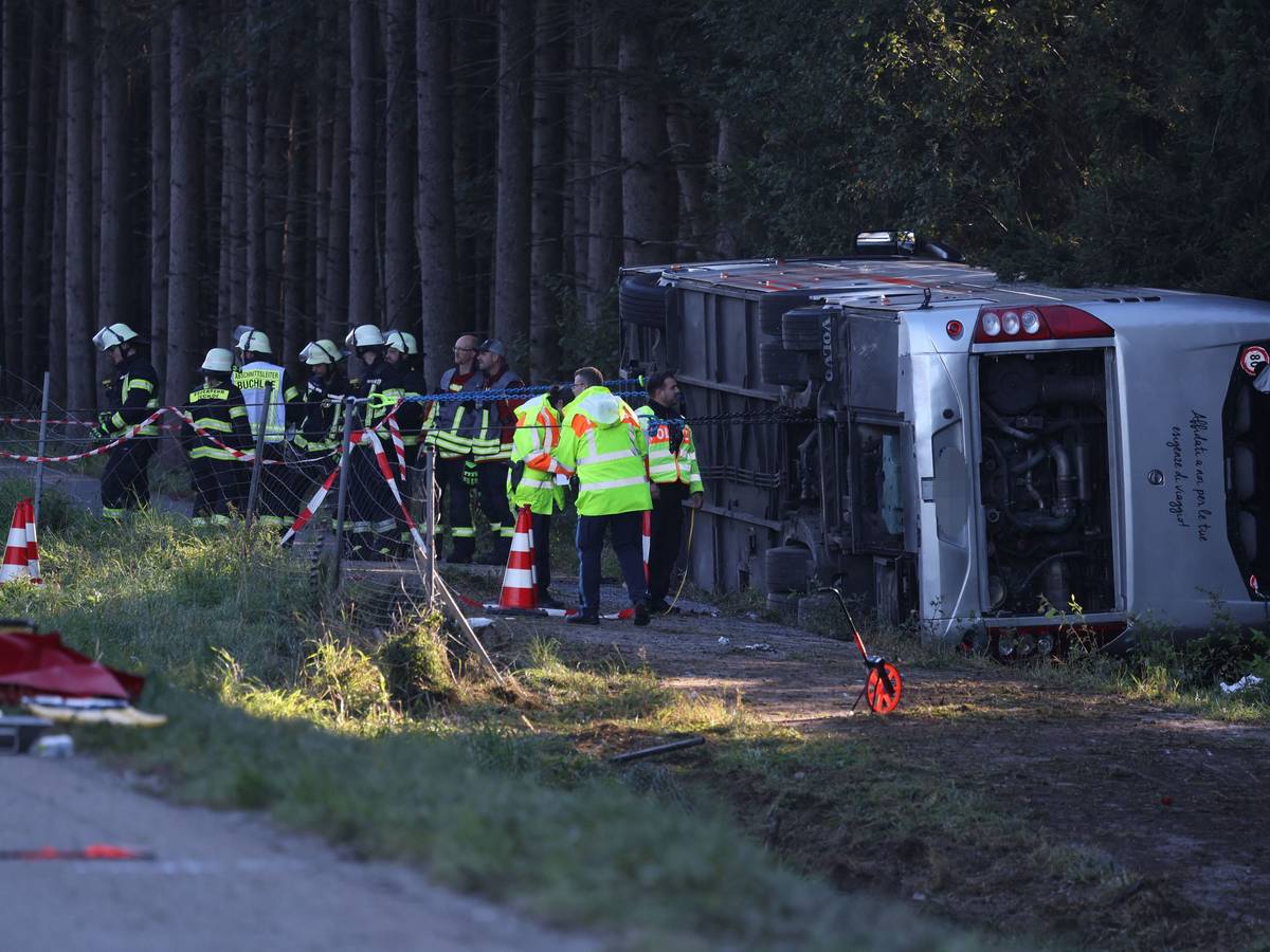 Kräfte von Feuerwehr und Polizei sind an einem Bus im Einsatz, der auf der Seite liegt.