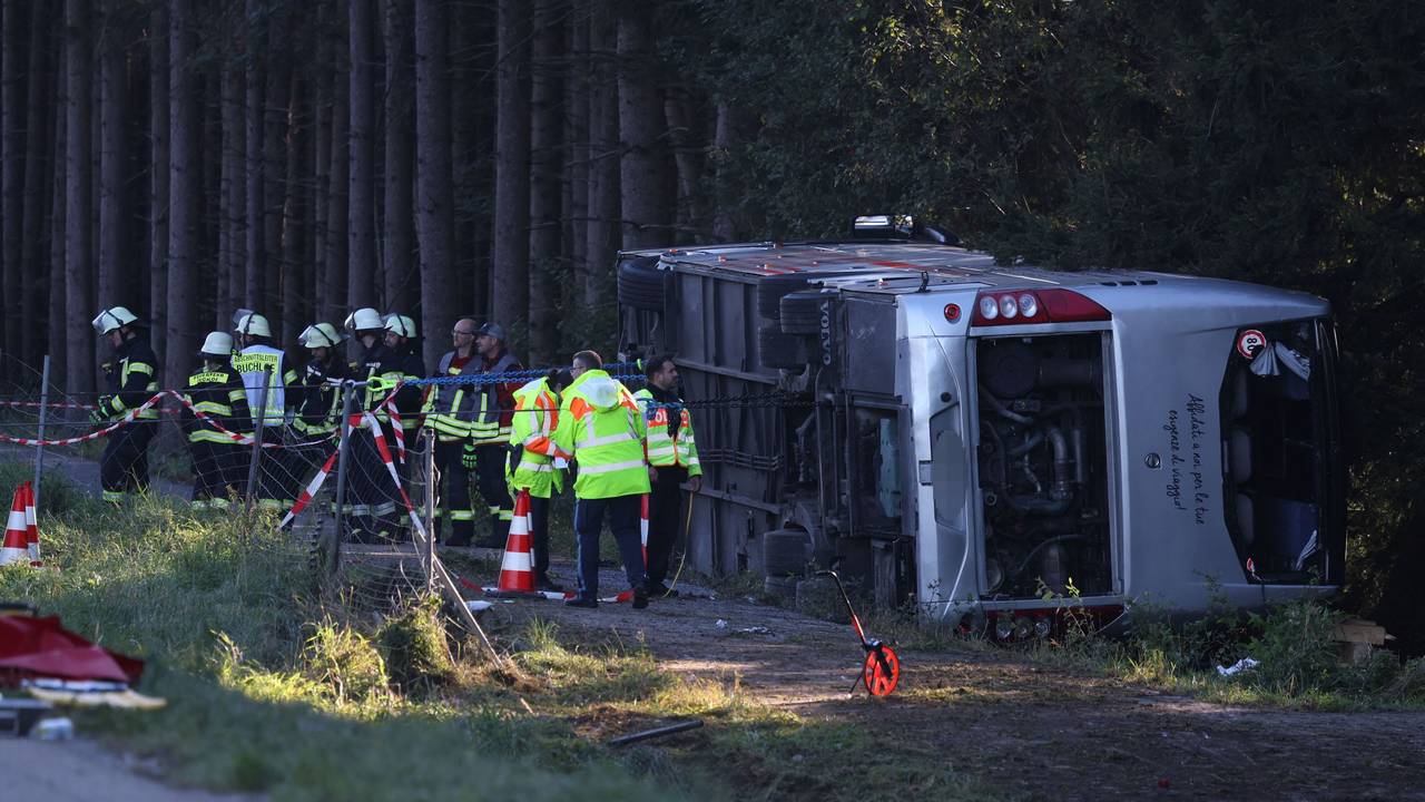Kräfte von Feuerwehr und Polizei sind an einem Bus im Einsatz, der auf der Seite liegt.