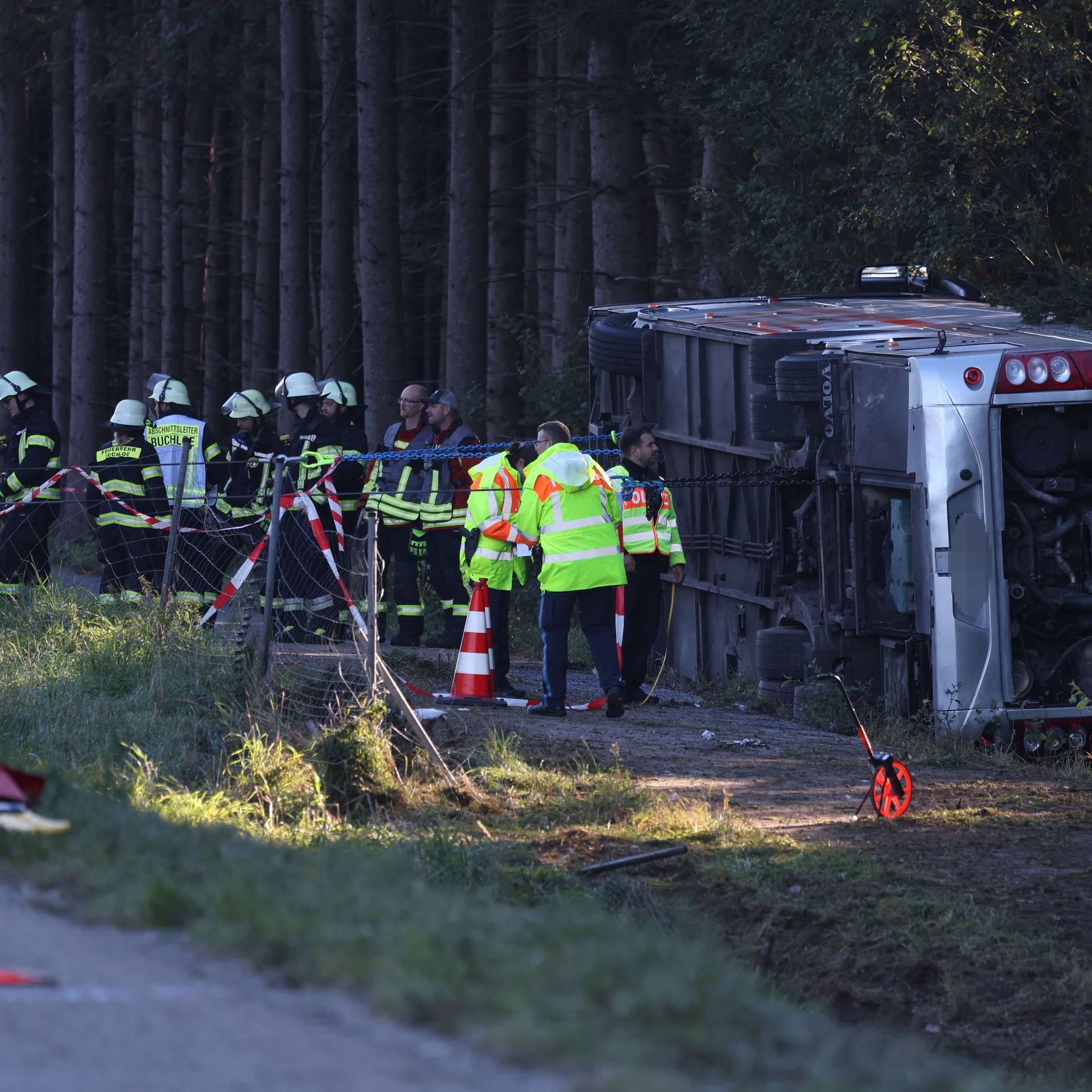 Kräfte von Feuerwehr und Polizei sind an einem Bus im Einsatz, der auf der Seite liegt.