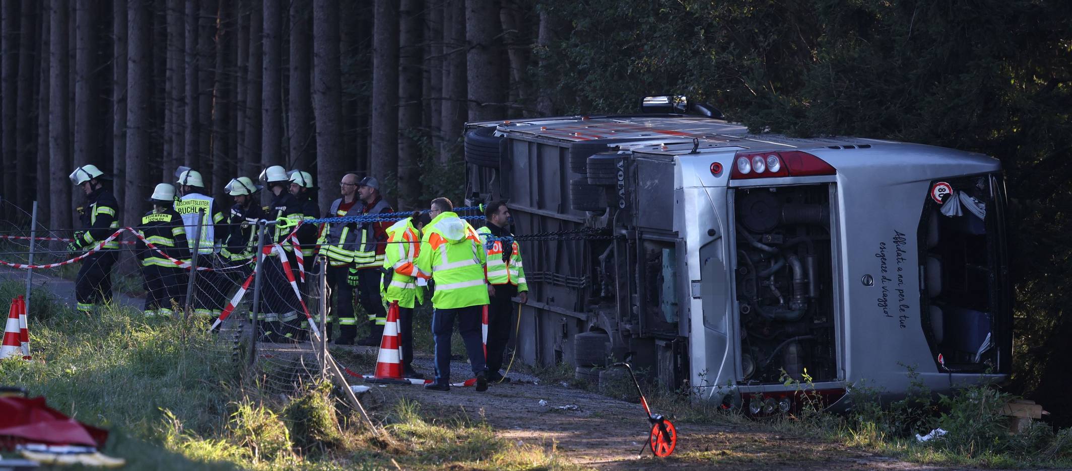 Kräfte von Feuerwehr und Polizei sind an einem Bus im Einsatz, der auf der Seite liegt.