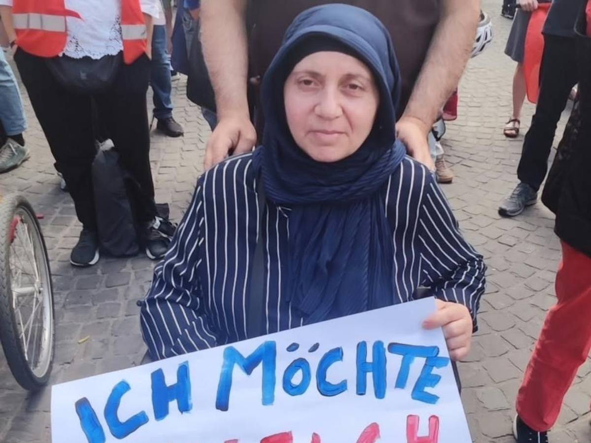 Die Frau, die im Rollstuhl sitzt, hält ein Plakat fest mit der Aufschrift „Ich möchte einfach nur wohnen“.