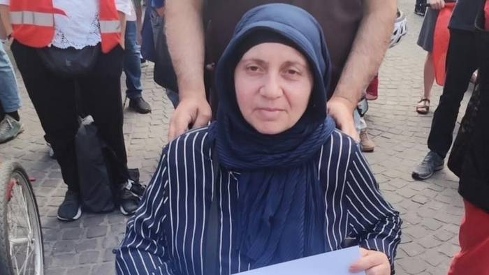 Die Frau, die im Rollstuhl sitzt, hält ein Plakat fest mit der Aufschrift „Ich möchte einfach nur wohnen“.