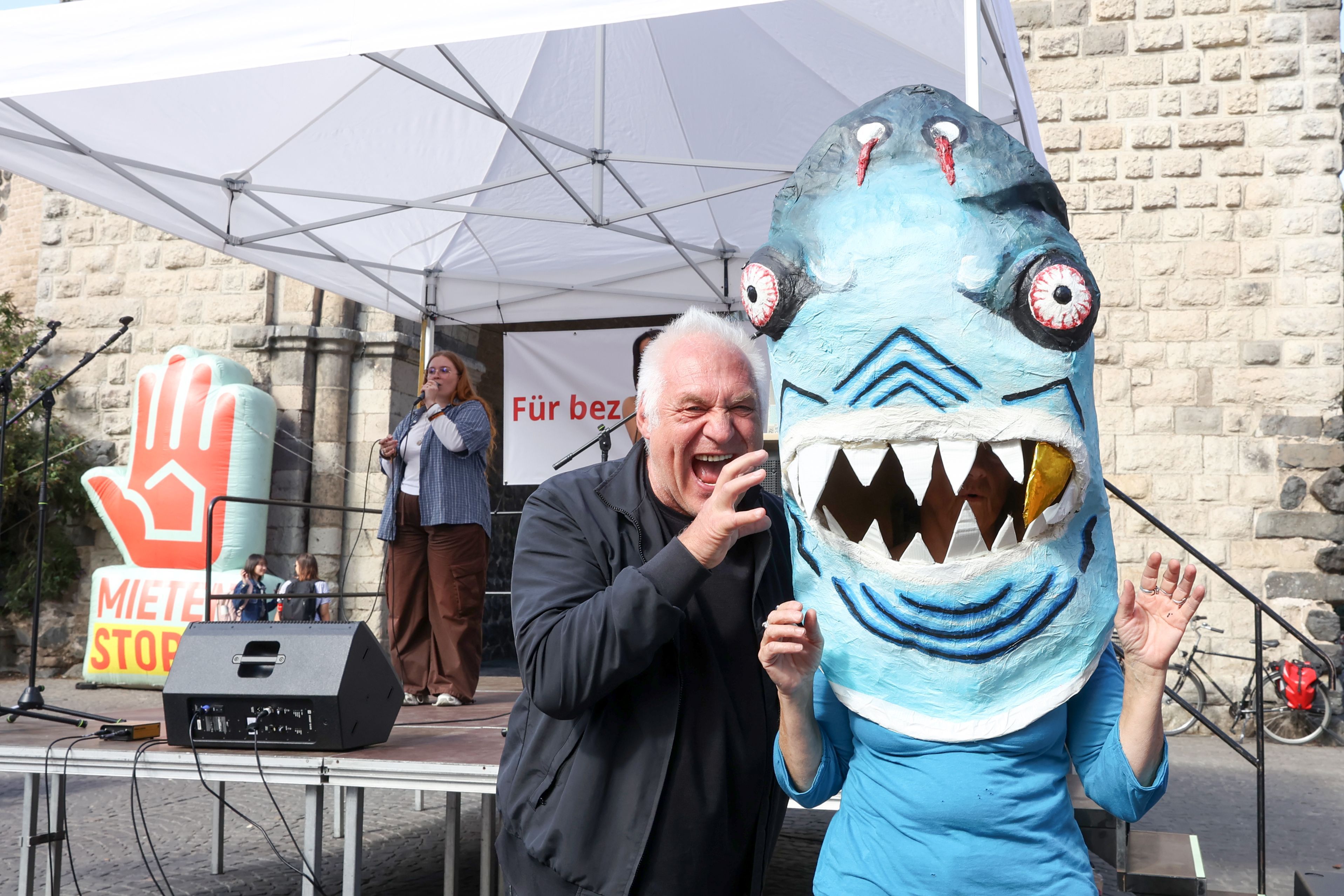 Kalle Gerigk greift symbolisch den Miethai an, einer Person, die unter einer Hai-Figur steckt.