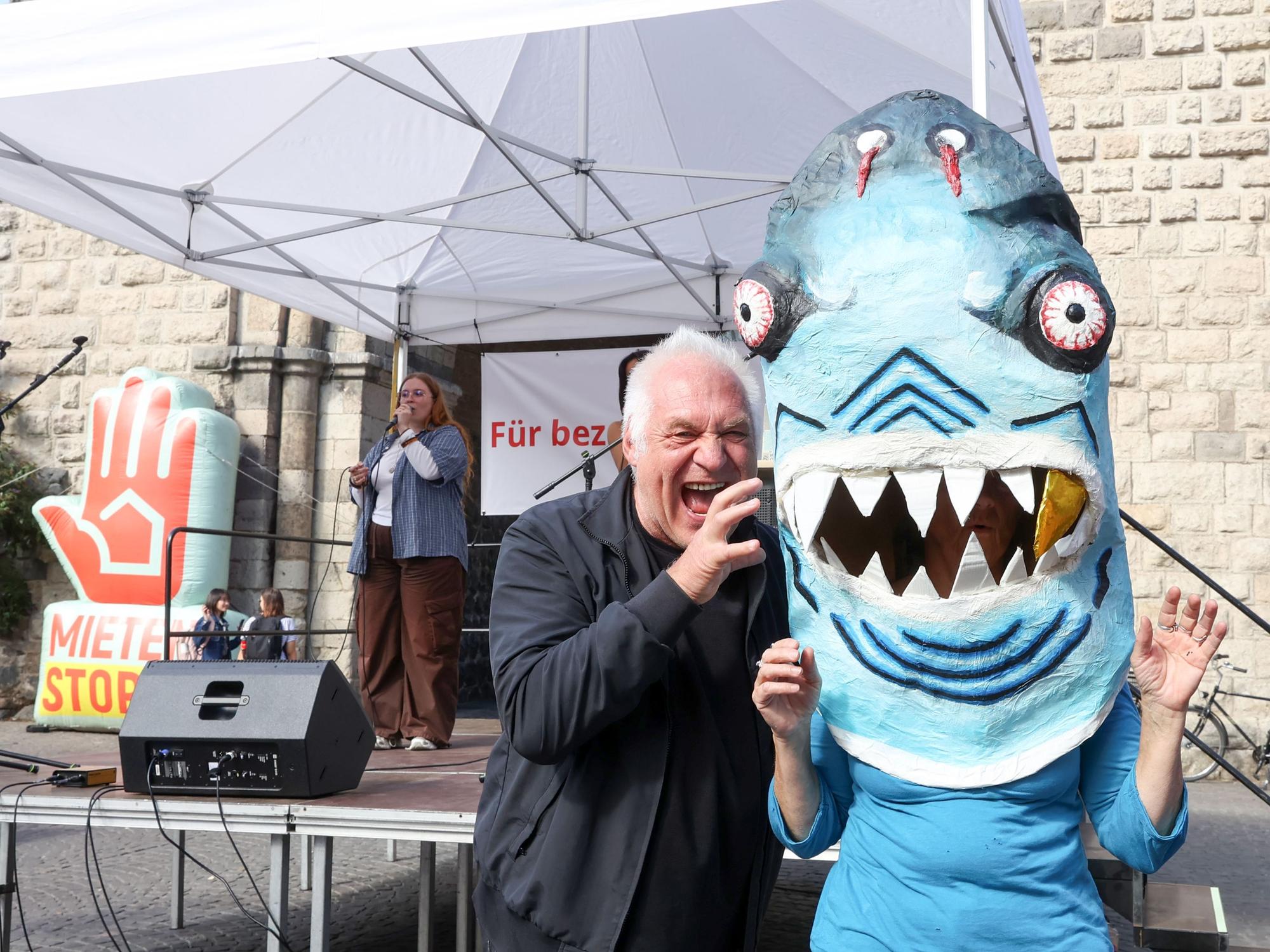 Kalle Gerigk greift symbolisch den Miethai an, einer Person, die unter einer Hai-Figur steckt.