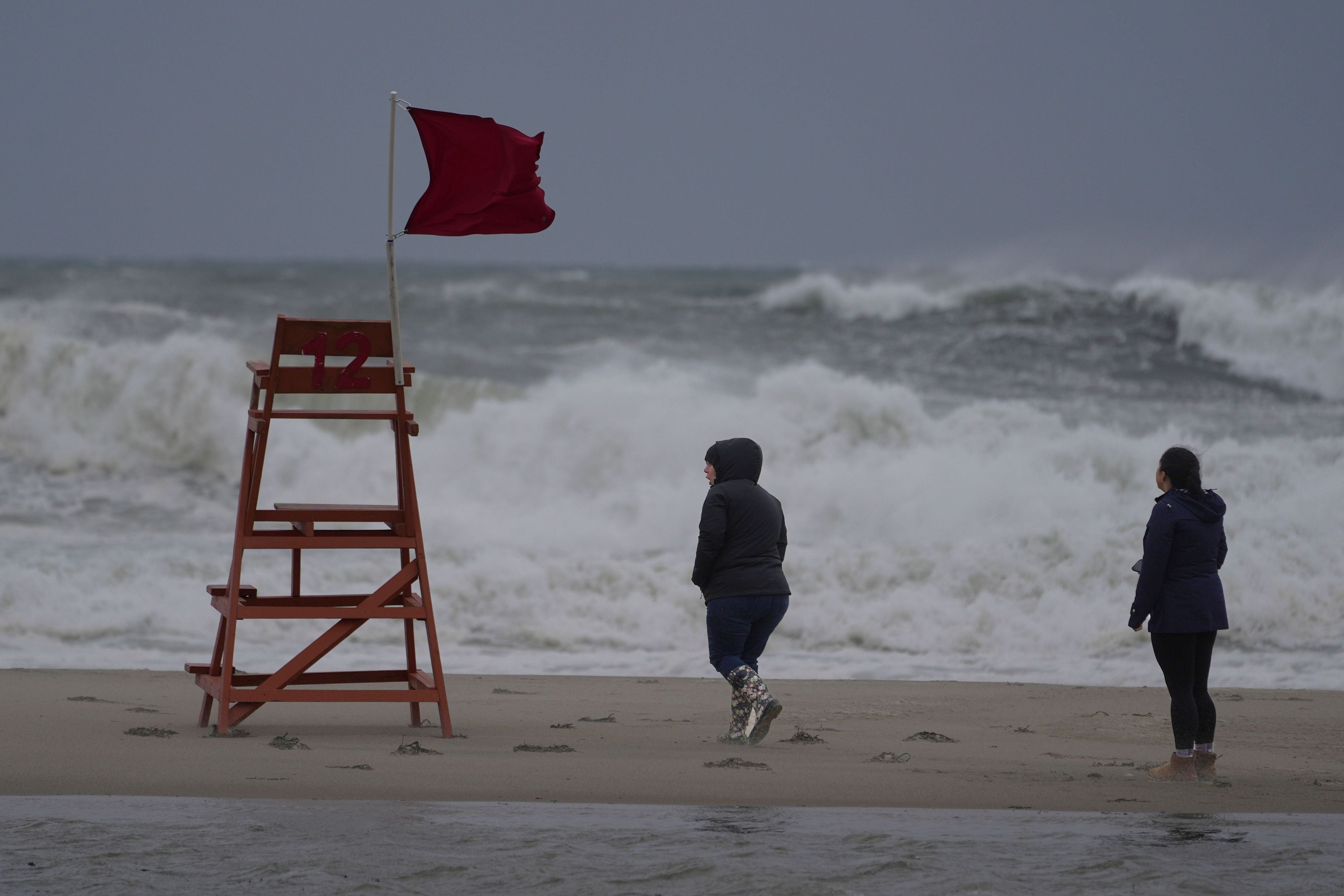 Spaziergänger gehen während eines Sturms am Strand der Hamptons entlang.