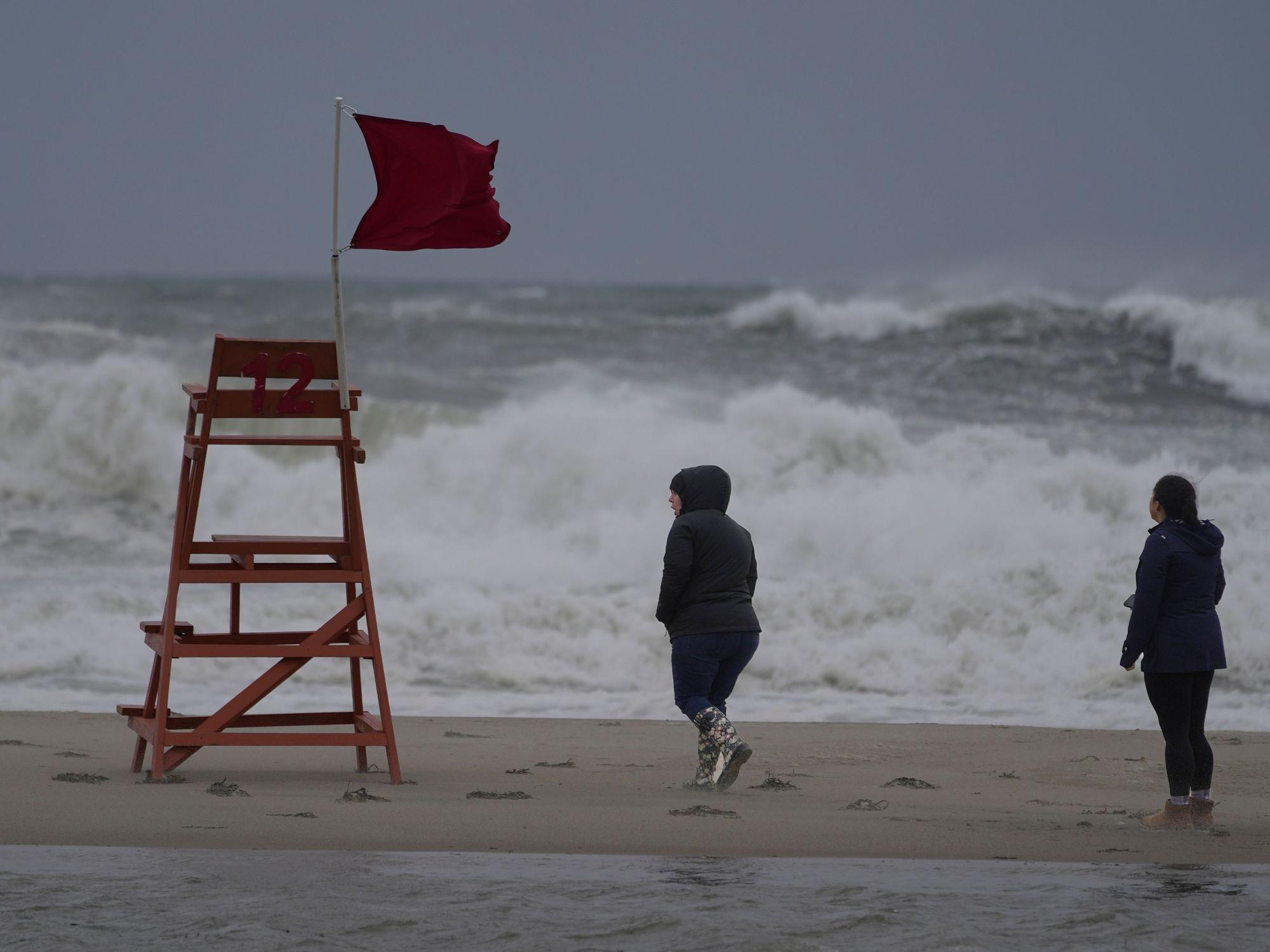 Spaziergänger gehen während eines Sturms am Strand der Hamptons entlang.