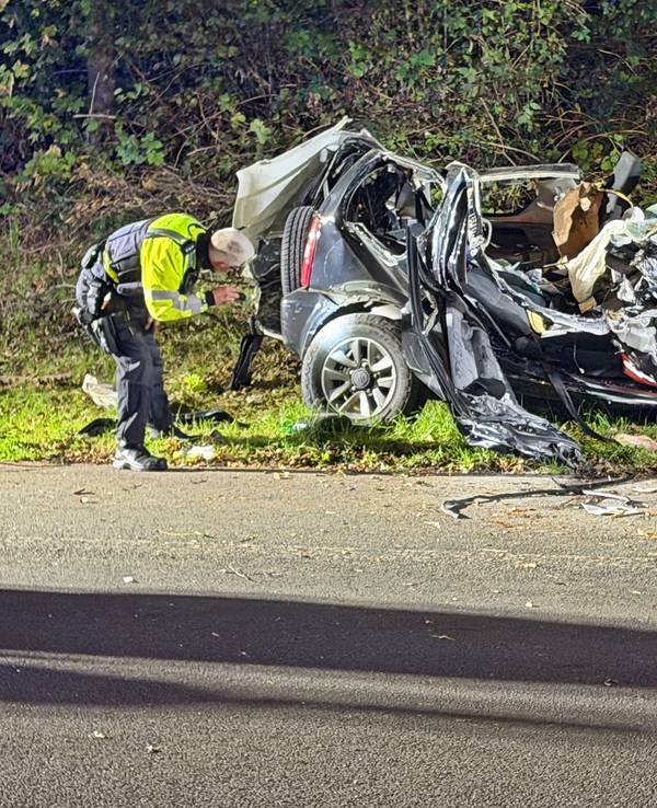 Ein Polizeibeamter untersucht ein zerstörtes Fahrzeug nach einem tödlichen Unfall an einer Autobahnausfahrt in Wuppertal.