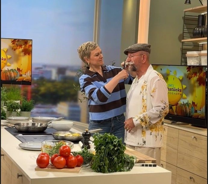 Karen Heinrichs rückt Horst Lichter mit einer Schere an den Schnauzbart.