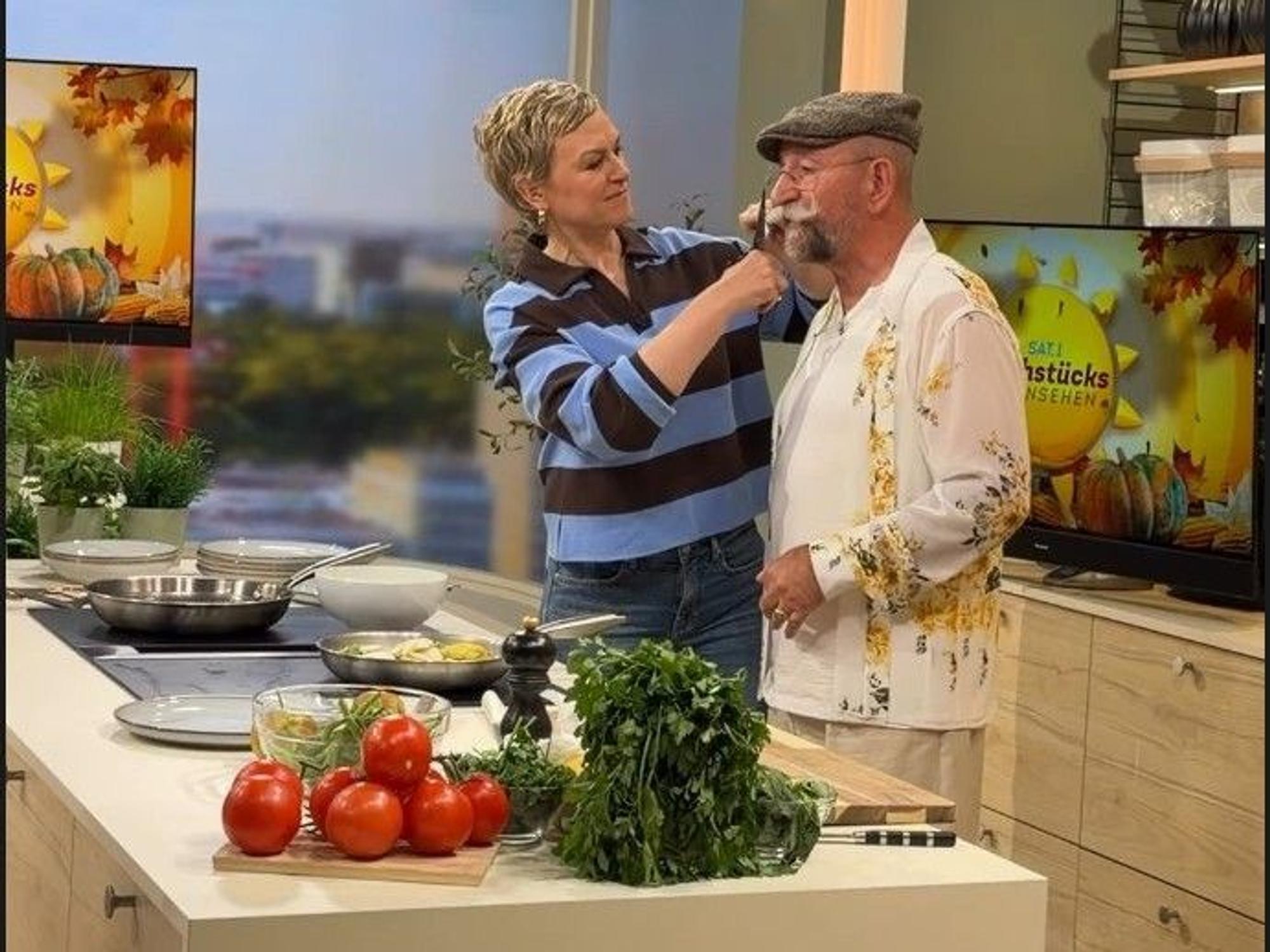 Karen Heinrichs rückt Horst Lichter mit einer Schere an den Schnauzbart.