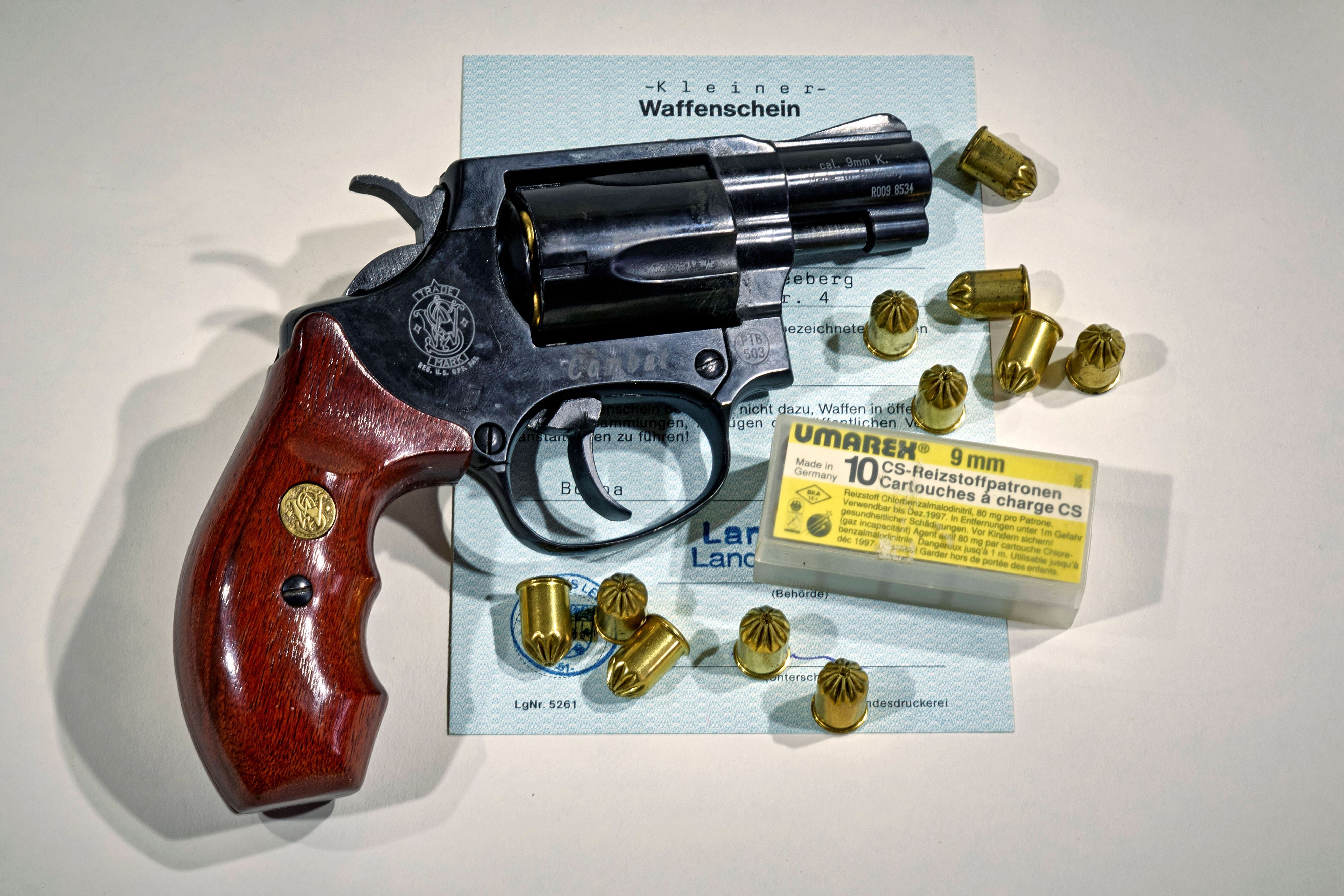 Eine Waffe der Marke Smith & Wesson samt Munition auf einem Dokument.