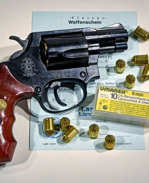 Eine Waffe der Marke Smith & Wesson samt Munition auf einem Dokument.