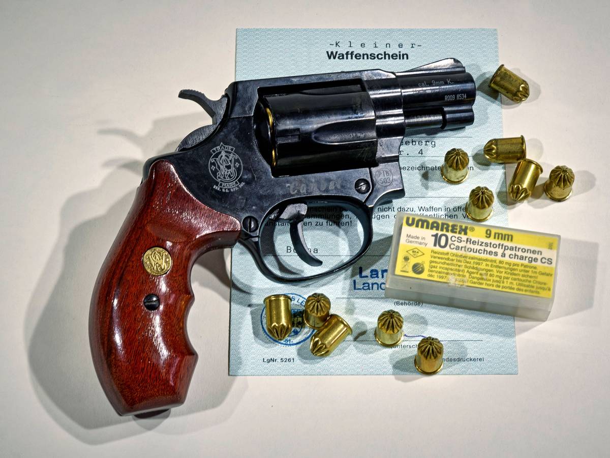 Eine Waffe der Marke Smith & Wesson samt Munition auf einem Dokument.