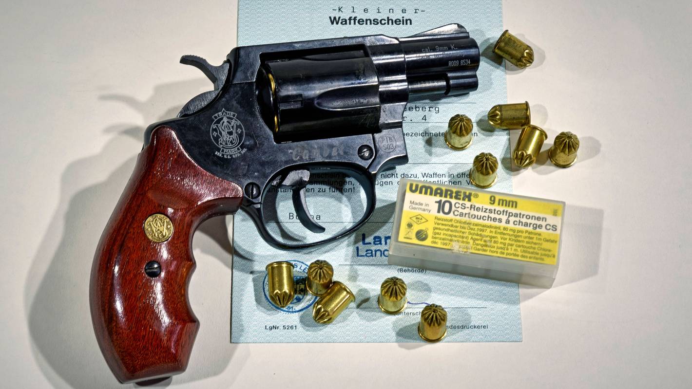 Eine Waffe der Marke Smith & Wesson samt Munition auf einem Dokument.