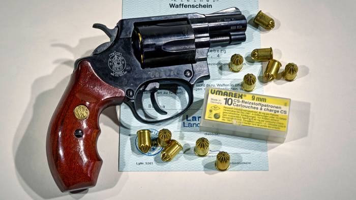 Eine Waffe der Marke Smith & Wesson samt Munition auf einem Dokument.