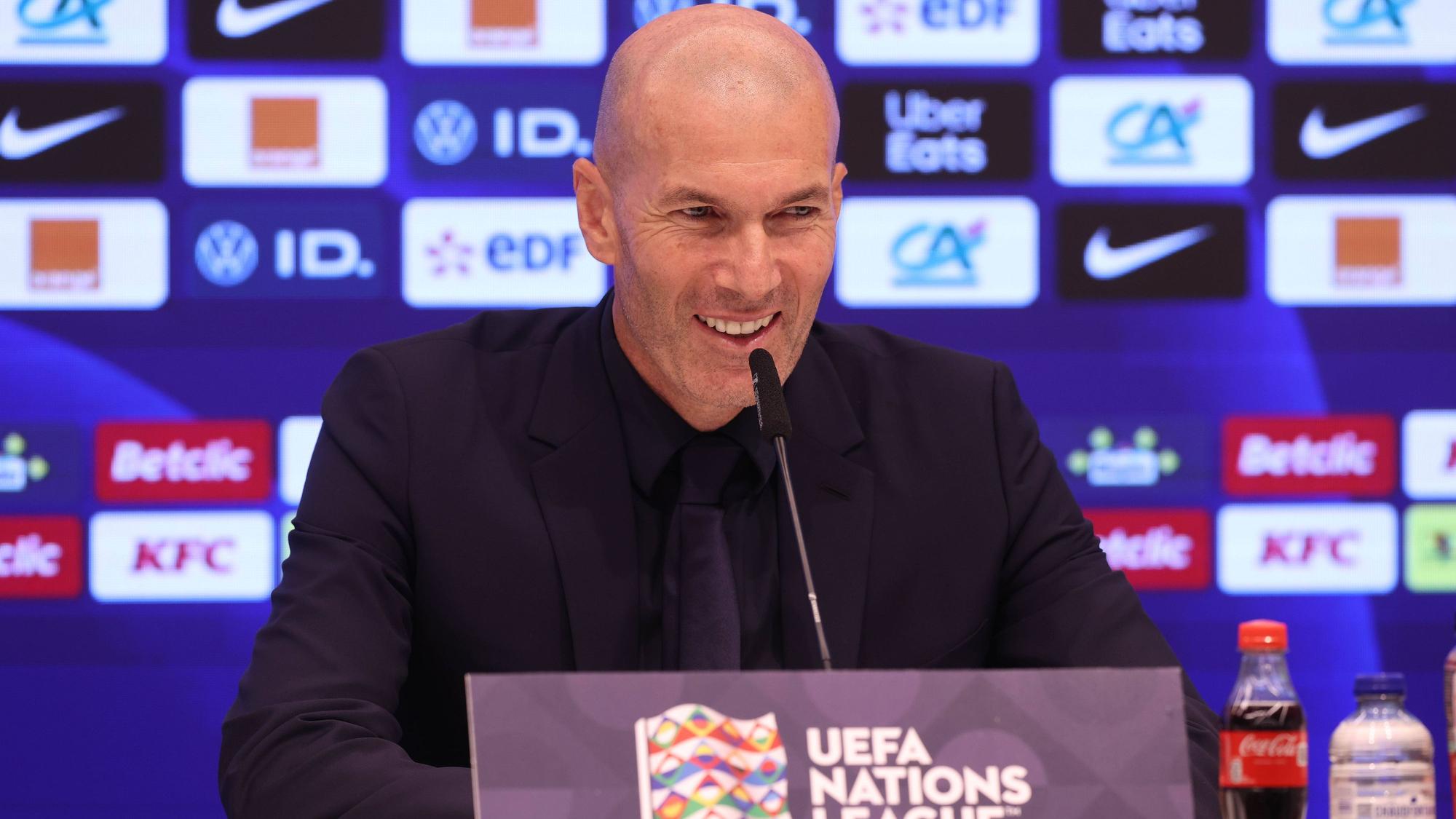 Zinedine Zidane lacht auf einer Pressekonferenz als französischer Nationaltrainer.