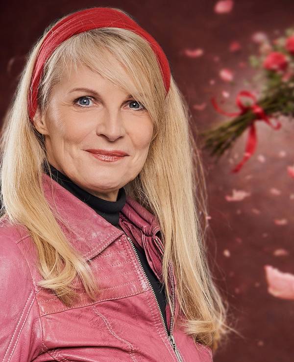 Eine Frau mit blonden Haare und rotem Haarband schaut in die Kamera