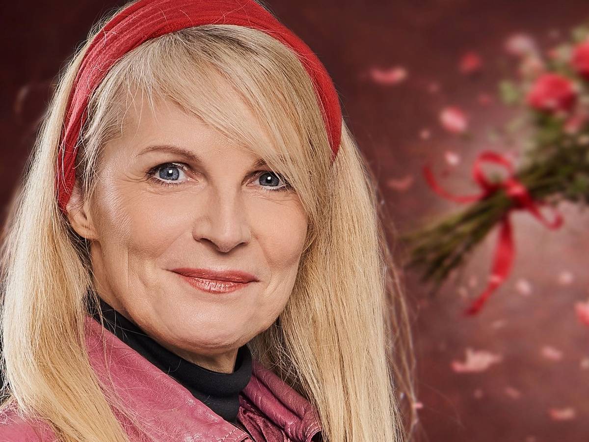 Eine Frau mit blonden Haare und rotem Haarband schaut in die Kamera