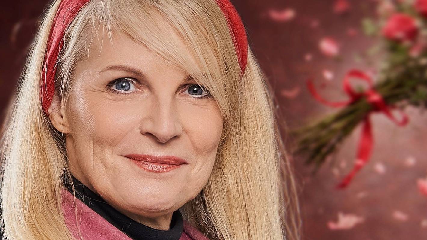 Eine Frau mit blonden Haare und rotem Haarband schaut in die Kamera
