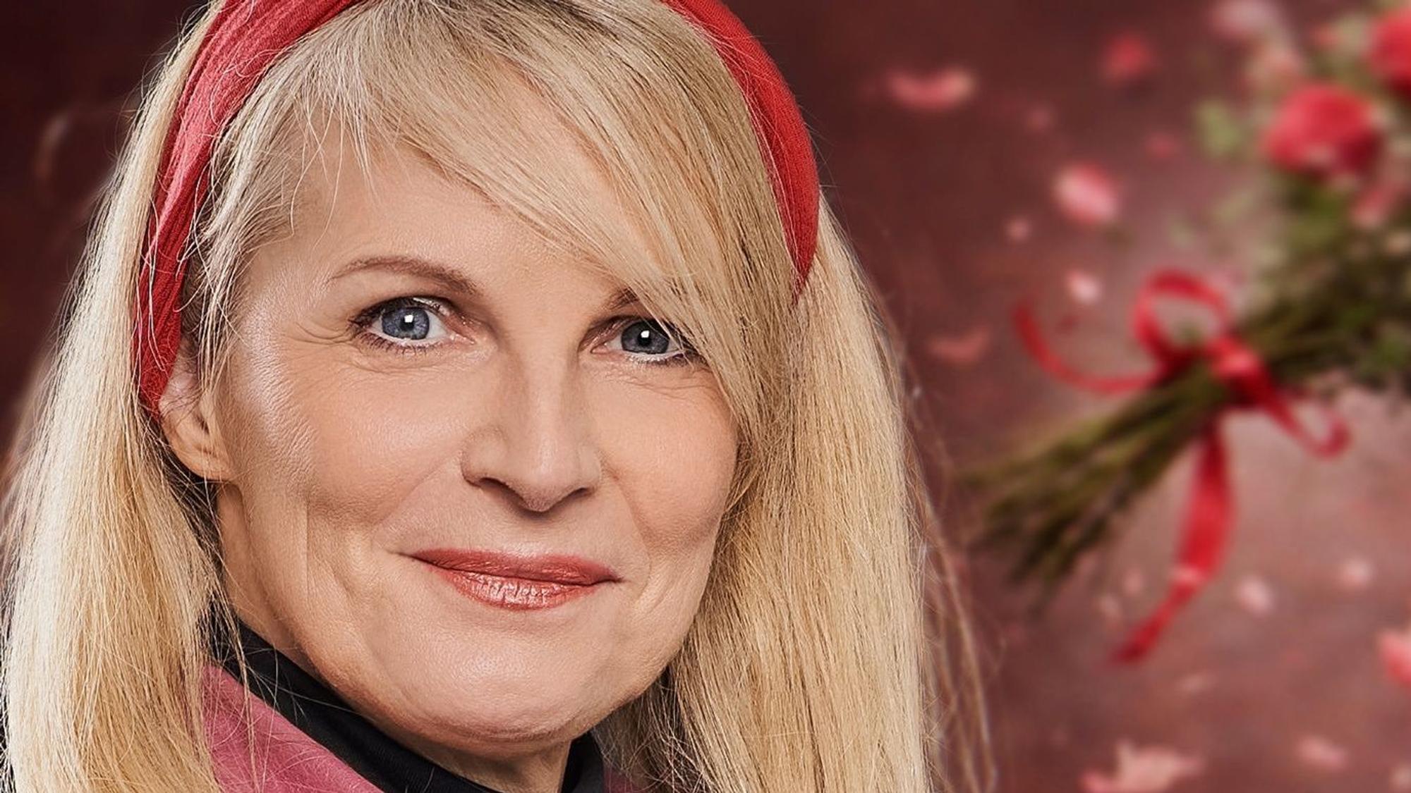 Eine Frau mit blonden Haare und rotem Haarband schaut in die Kamera