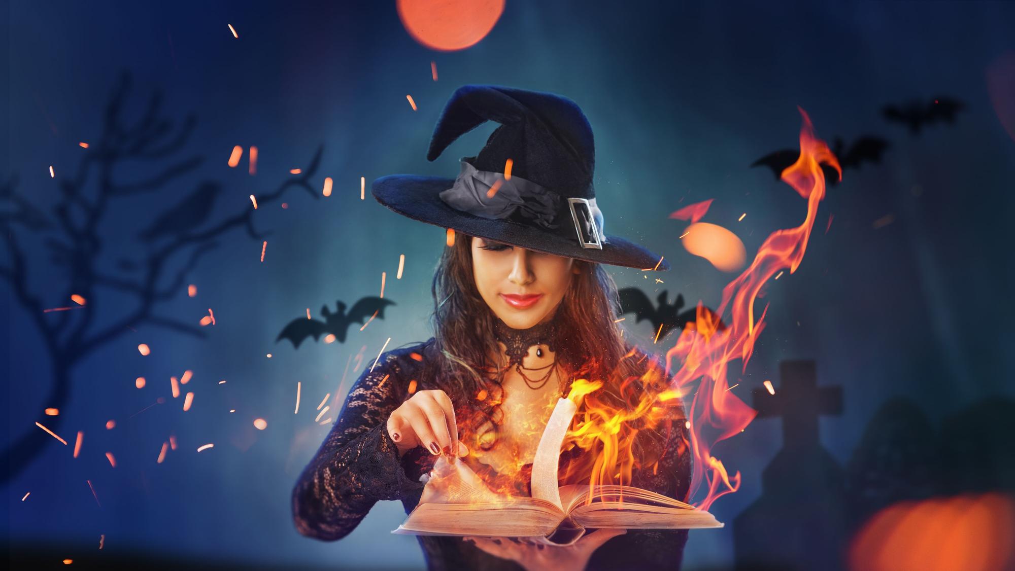 Eine als Hexe verkleidete Frau vor einem brennenden Buch