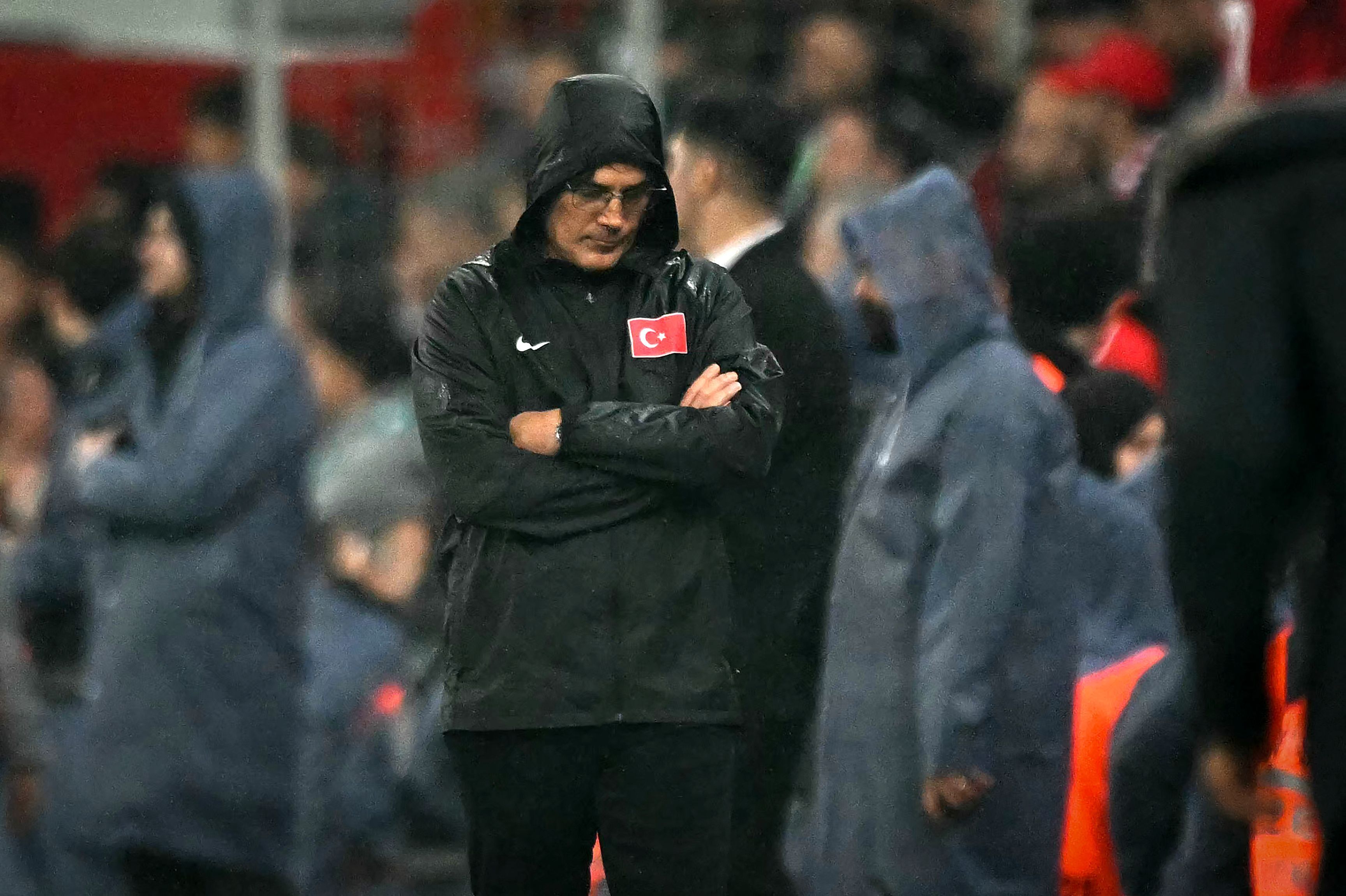 Vincenzo Montella steht mit verschränkten Armen, gesenktem Kopf und einer Regenjacke am Seitenrand.