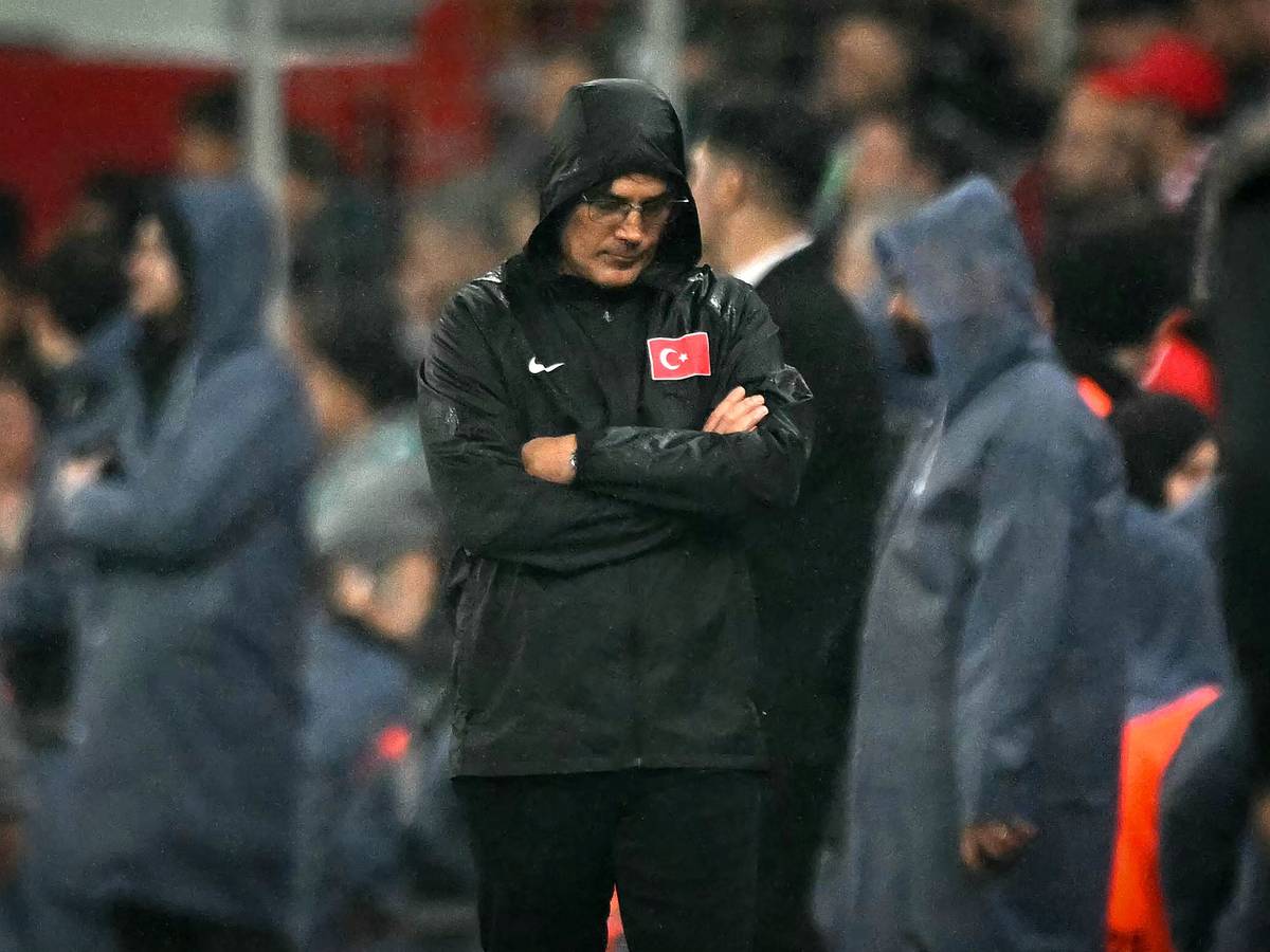 Vincenzo Montella steht mit verschränkten Armen, gesenktem Kopf und einer Regenjacke am Seitenrand.