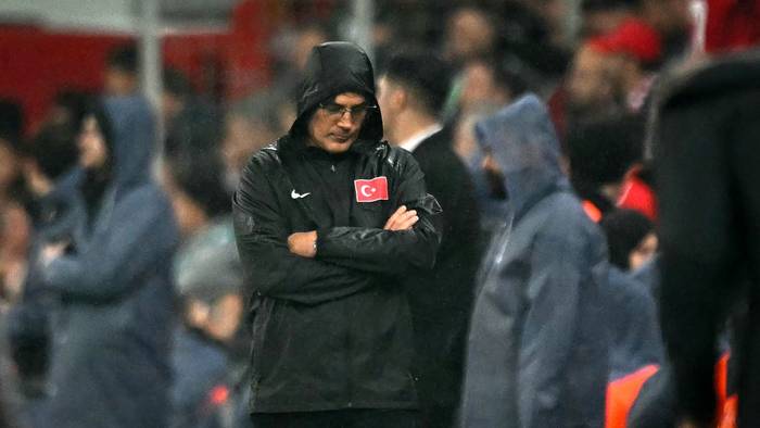 Vincenzo Montella steht mit verschränkten Armen, gesenktem Kopf und einer Regenjacke am Seitenrand.