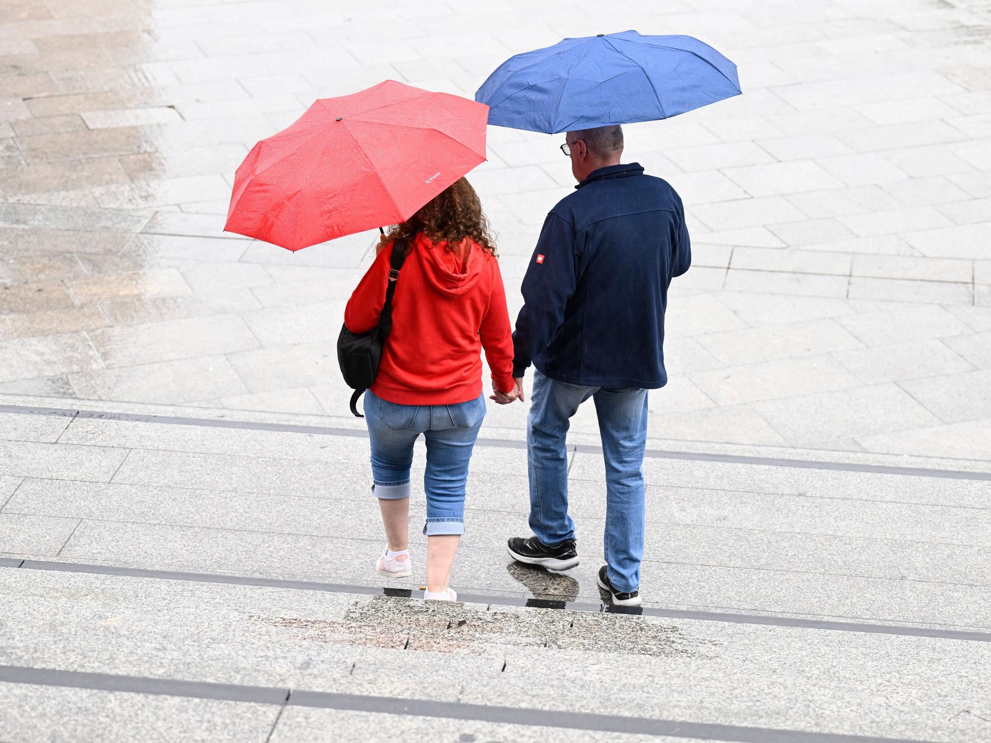 Spaziergänger schützen sich auf dem Kölner Bahnhofsvorplatz mit Schirmen vor dem Regen. Die Meteorologen sagen für die nächste Woche wechselhaftes Wetter mit Regen voraus. (Symbolfoto)
