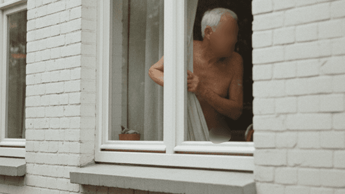 Das maschinell erzeugte Symbolbild zeigt einen älteren Herren, der durch ein Fenster schaut. Elf Jahre lang wurde eine Witwe in England von ihrem Nachbarn belästigt.