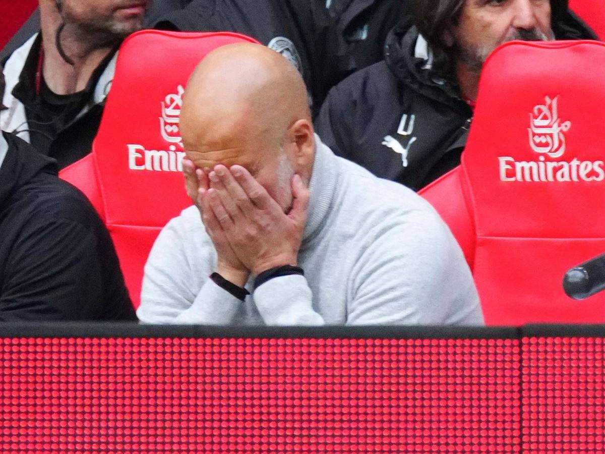 Pep Guardiola vergräbt sein Gesicht in seinen Händen.