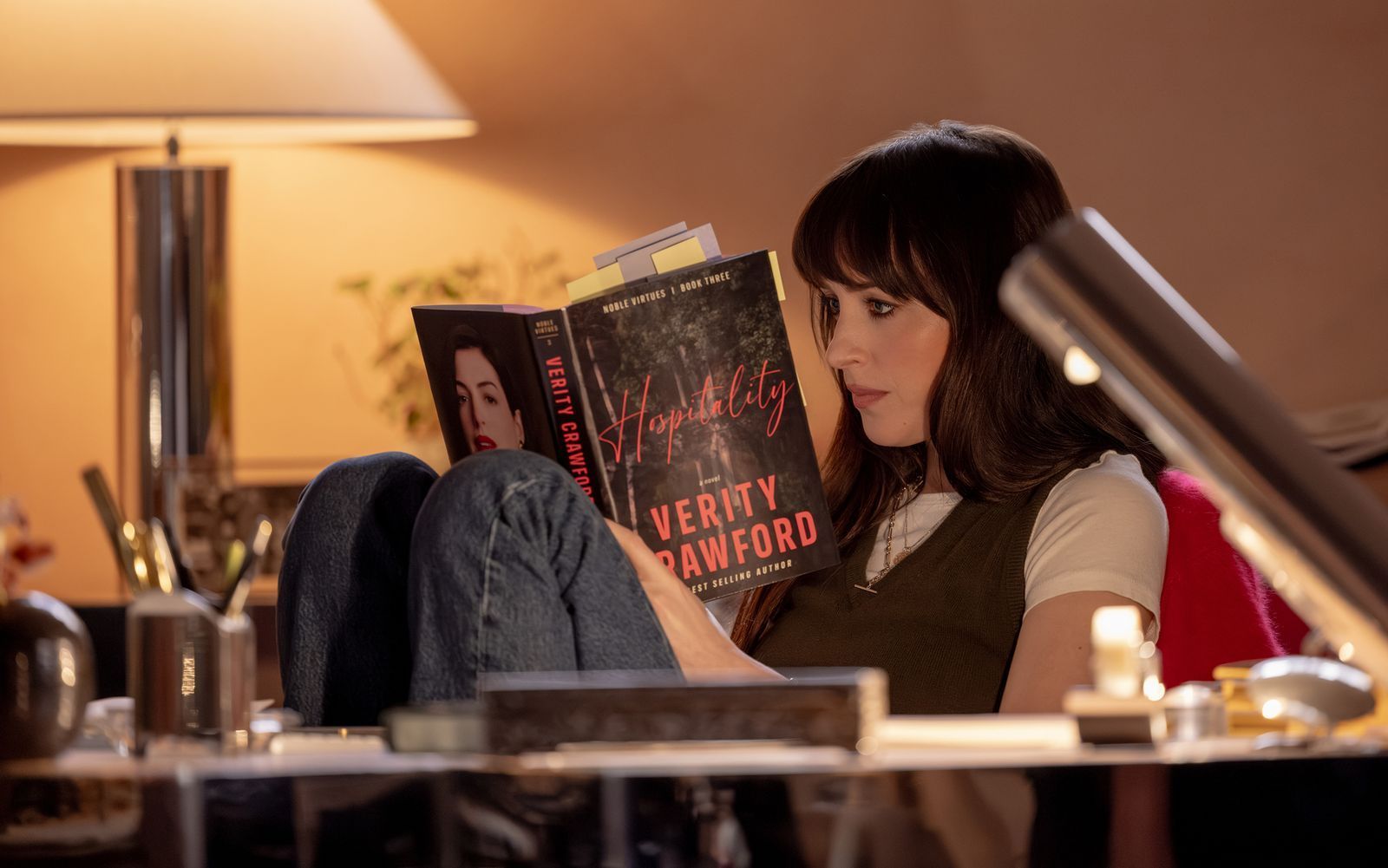 Lowen (Dakota Johnson) liest einen der Bestseller von Verity Crawford - die Frau, deren letzten Roman sie vollenden soll. (Bild: 2026 Amazon Content Services LLC/Alisha Wetherill)