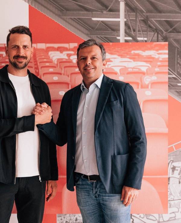 Patrick Fabian und Samir Arabi geben sich einen Handschlag und schauen in die Kamera.