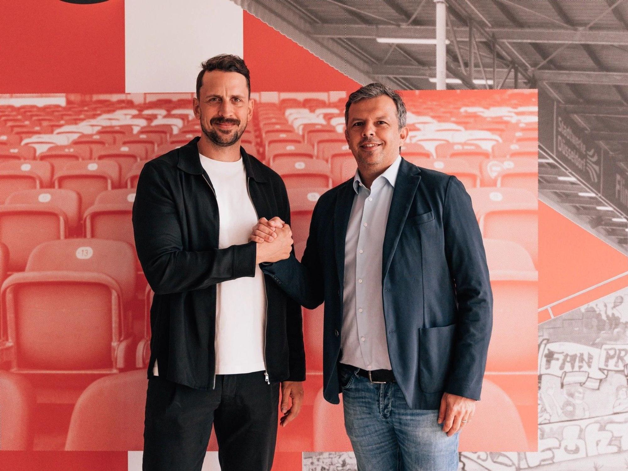 Patrick Fabian und Samir Arabi geben sich einen Handschlag und schauen in die Kamera.