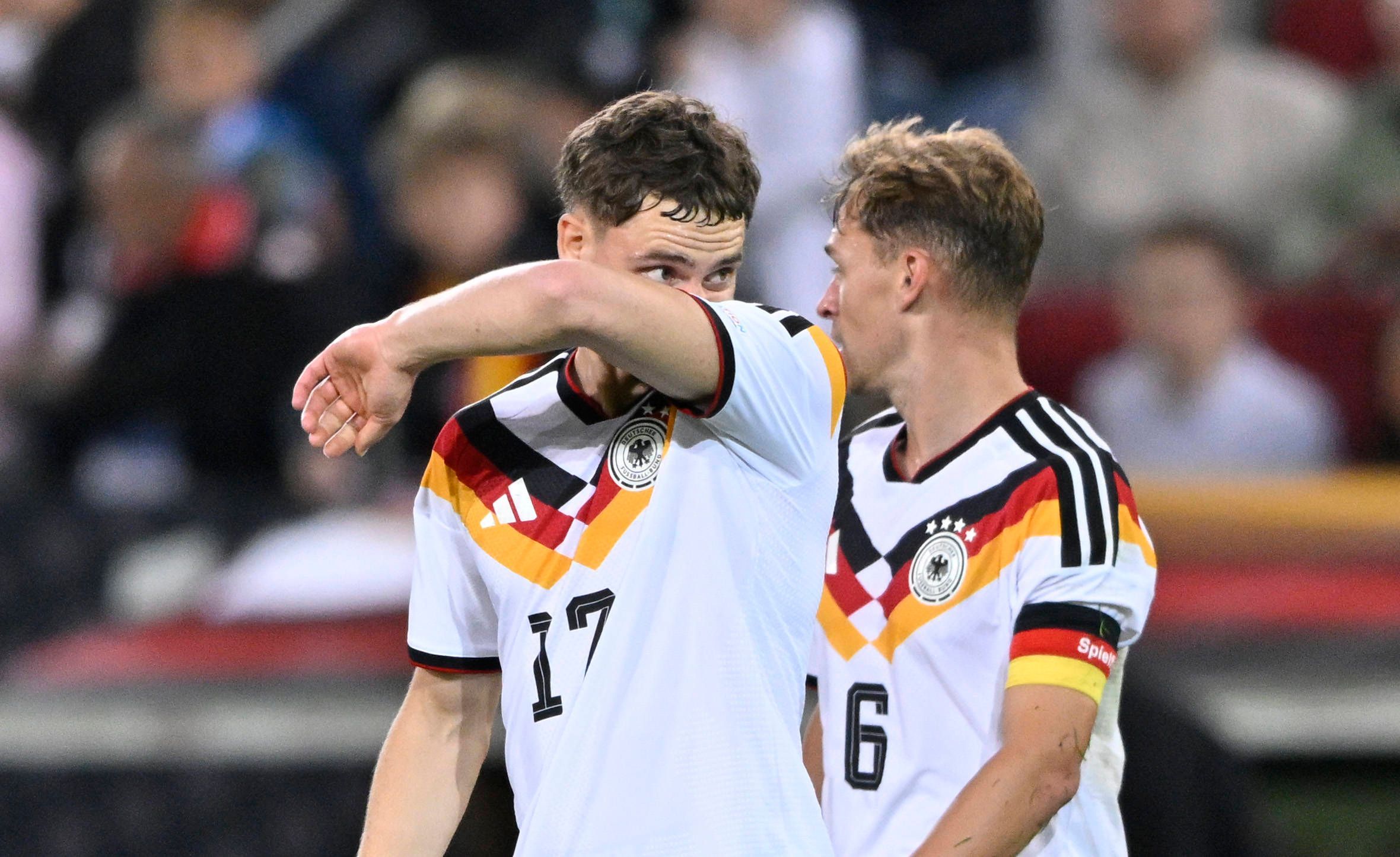 Florian Wirtz wischt sich mit seinem Arm durch das Gesicht, Joshua Kimmich schaut ihn an.