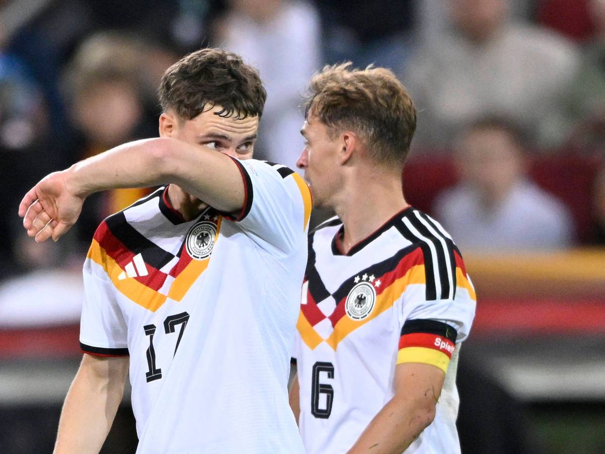Florian Wirtz wischt sich mit seinem Arm durch das Gesicht, Joshua Kimmich schaut ihn an.