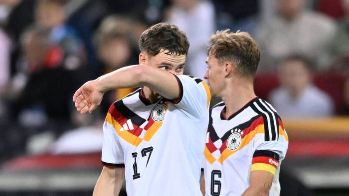 Florian Wirtz wischt sich mit seinem Arm durch das Gesicht, Joshua Kimmich schaut ihn an.