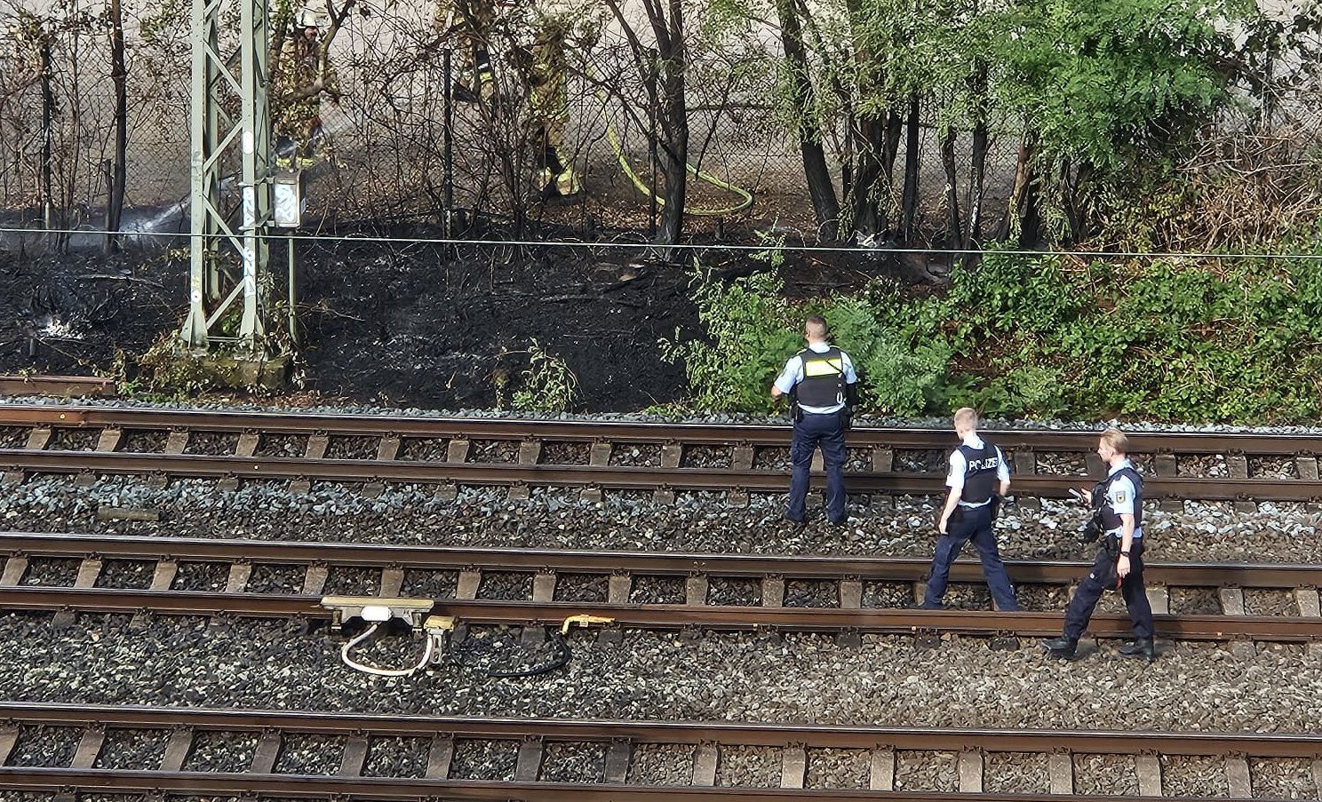 Das Feuer an der Bahnstrecke wurde inzwischen gelöscht. Einsatzkräfte der Polizei bei der Spurensuche.