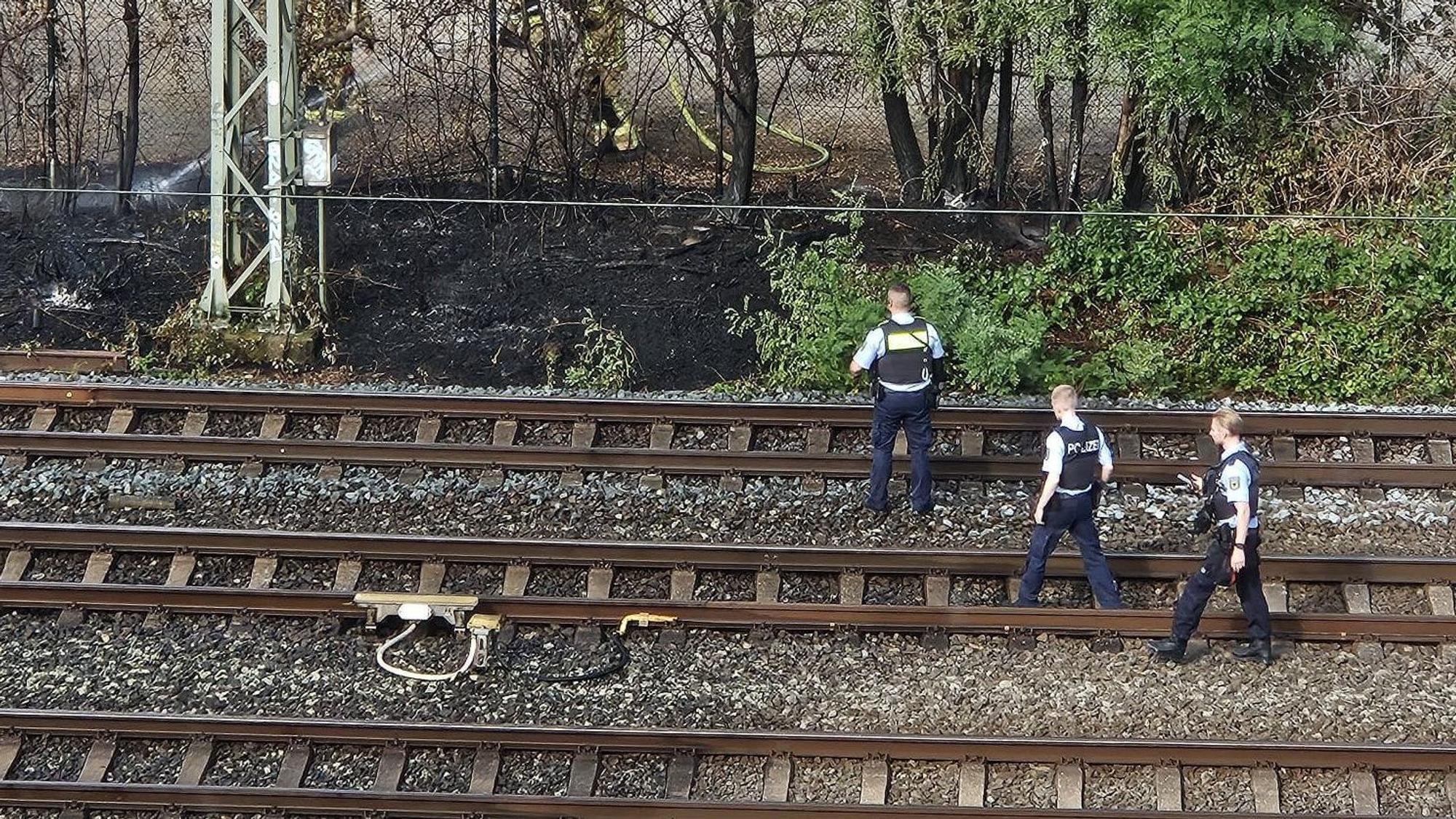 Das Feuer an der Bahnstrecke wurde inzwischen gelöscht. Einsatzkräfte der Polizei bei der Spurensuche.