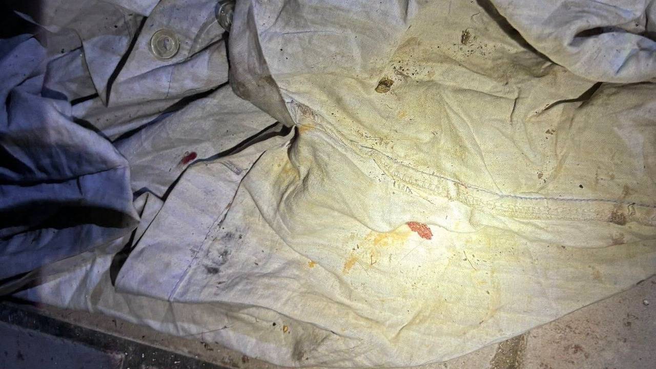 Auf einem Hemd, das auf dem Boden liegt, sind Blutflecken.
