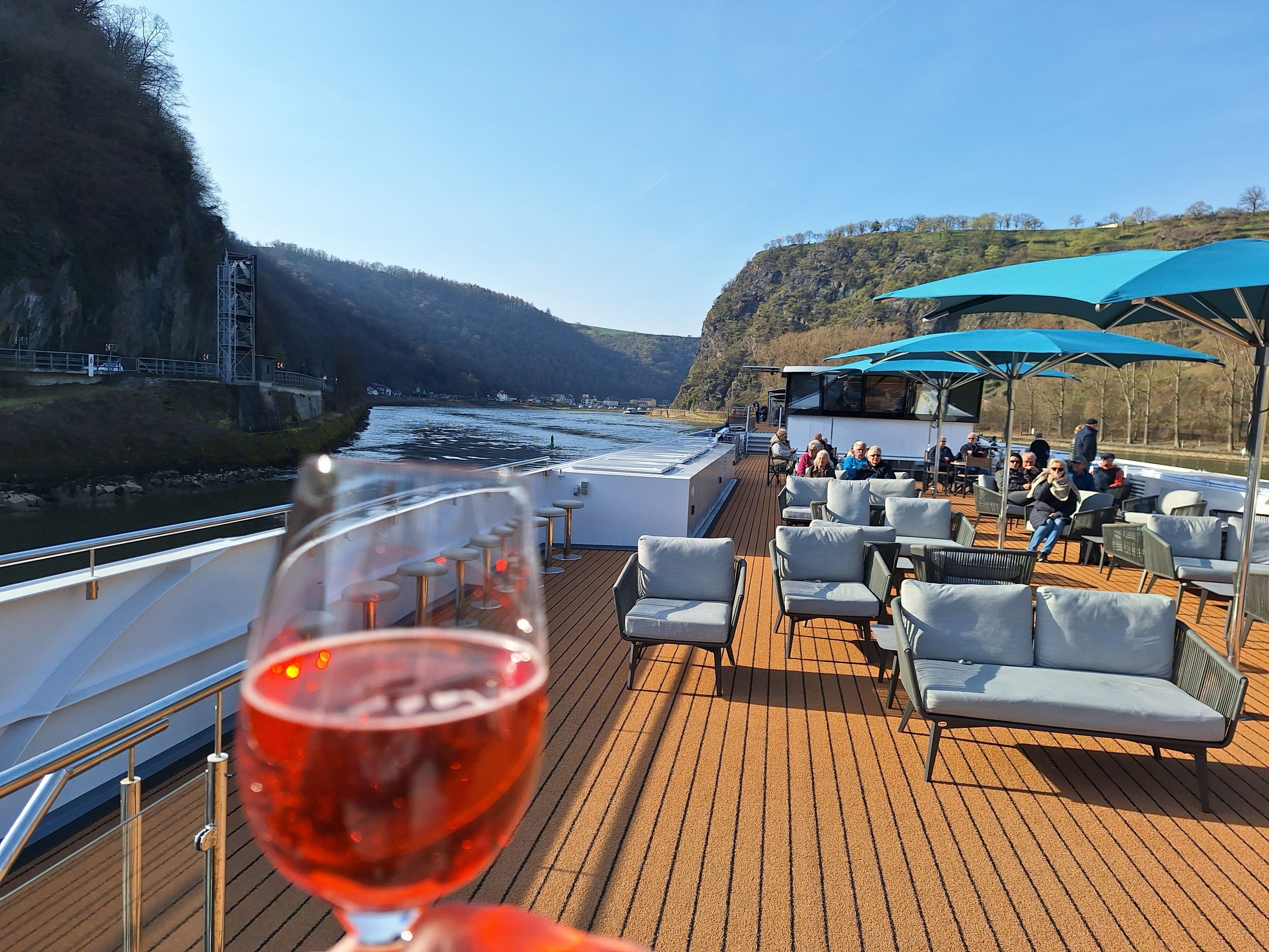 Blick über ein Schiffsdeck und auf die Hügel des Mittelrheintales