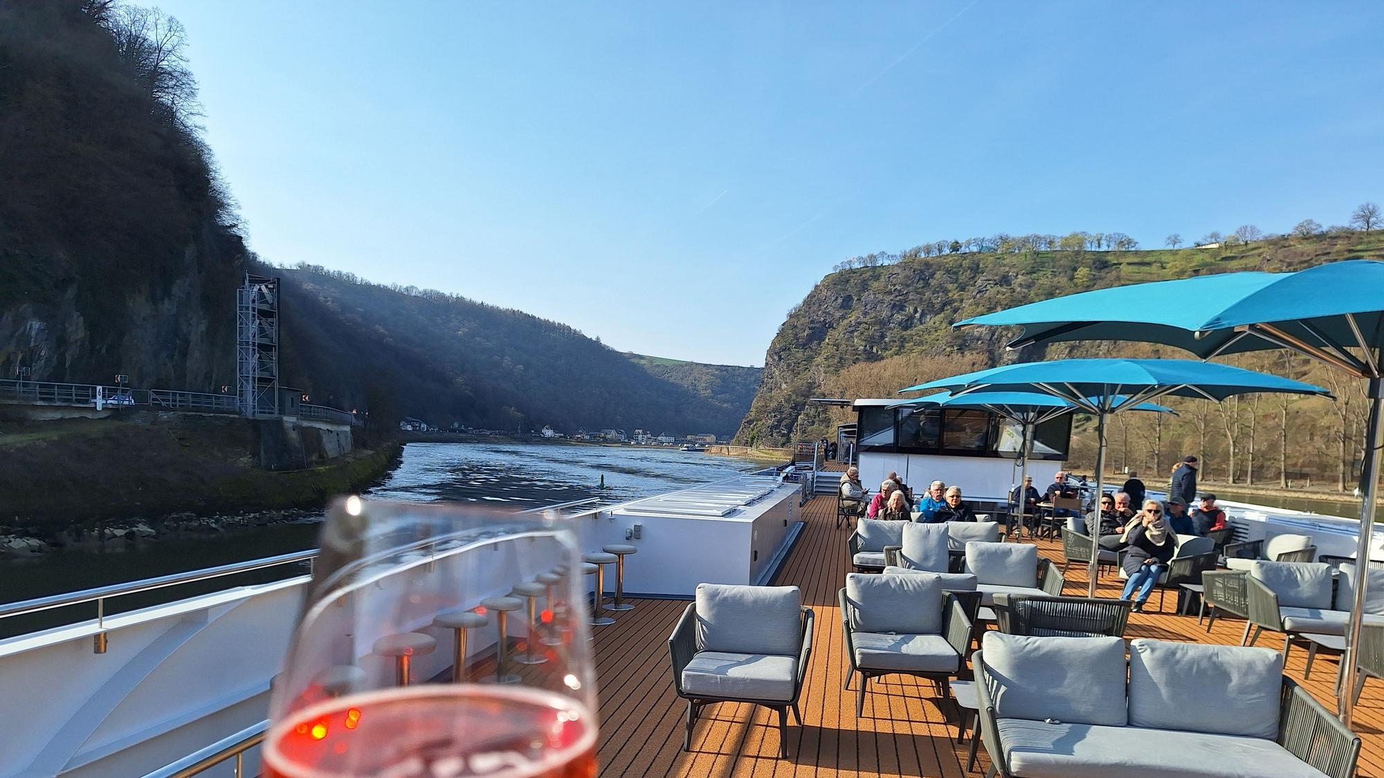 Blick über ein Schiffsdeck und auf die Hügel des Mittelrheintales