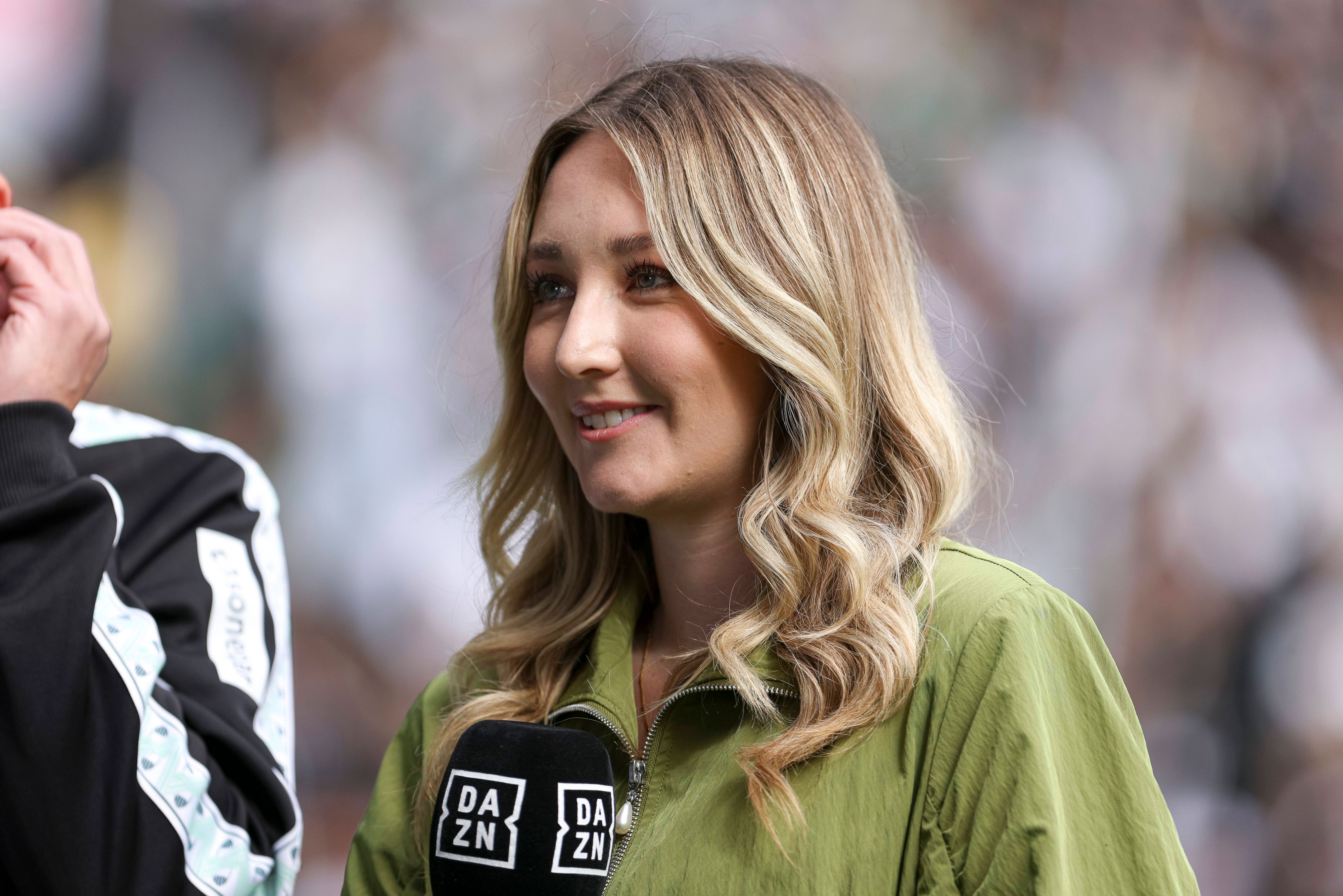 Lisa Tellers steht mit DAZN-Mikrofon am Spielfeldrand.