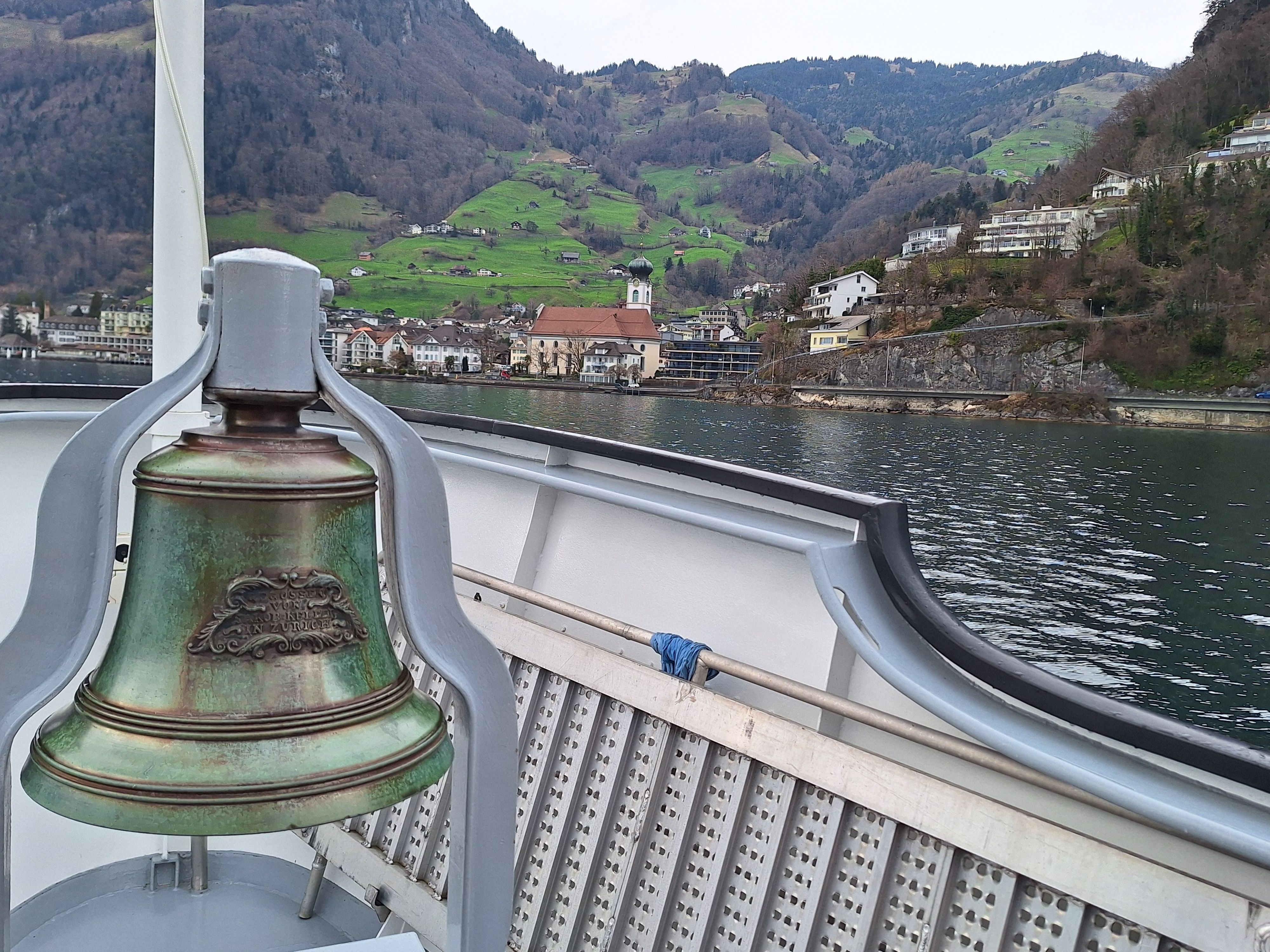 Blick von einem Schiff auf eine grüne Alm mit Kirchturm