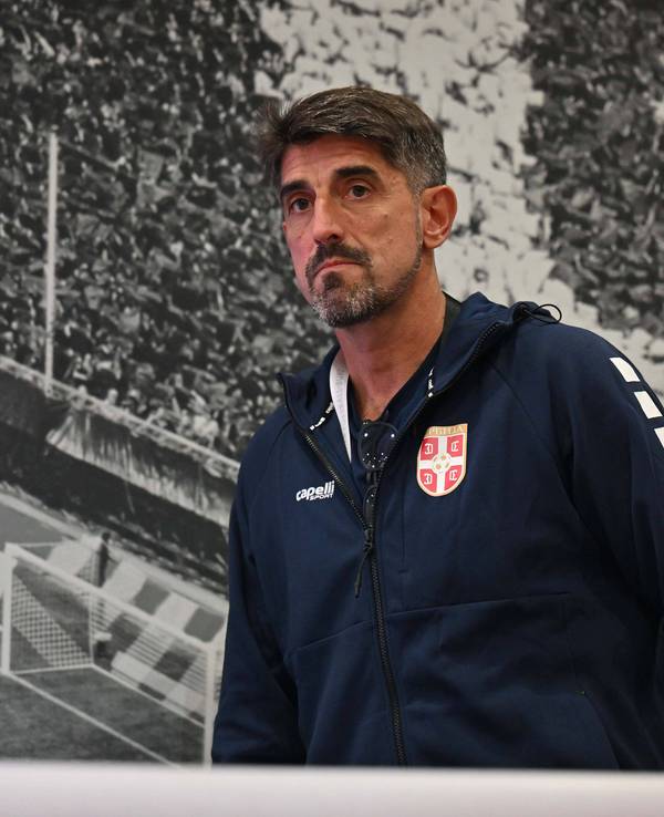 Veljko Paunović vor einer Wand, auf der eine Tribüne zu sehen ist.